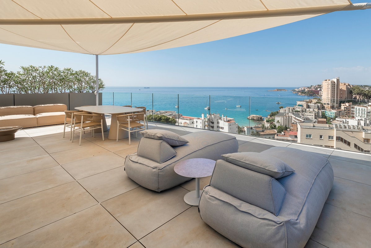 Rooftop terrace in Cala Mayor with a large shade canopy, lounge seating, and a dining area overlooking the Mediterranean Sea.