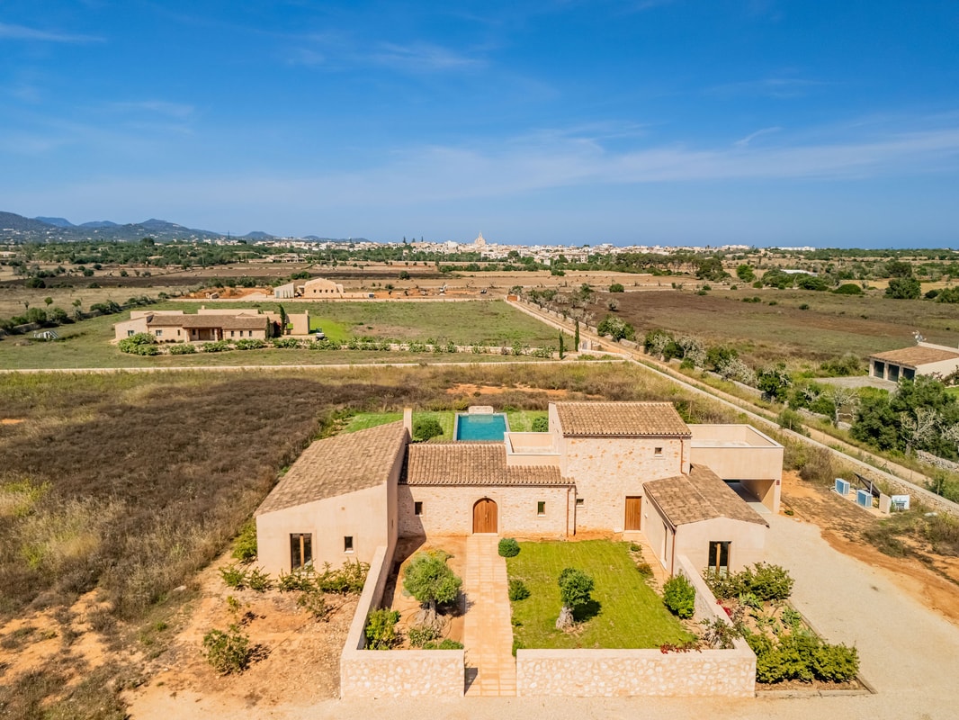 Aerial view of a traditional stone finca with tiled roofs, a private swimming pool, and landscaped gardens in a rural setting.