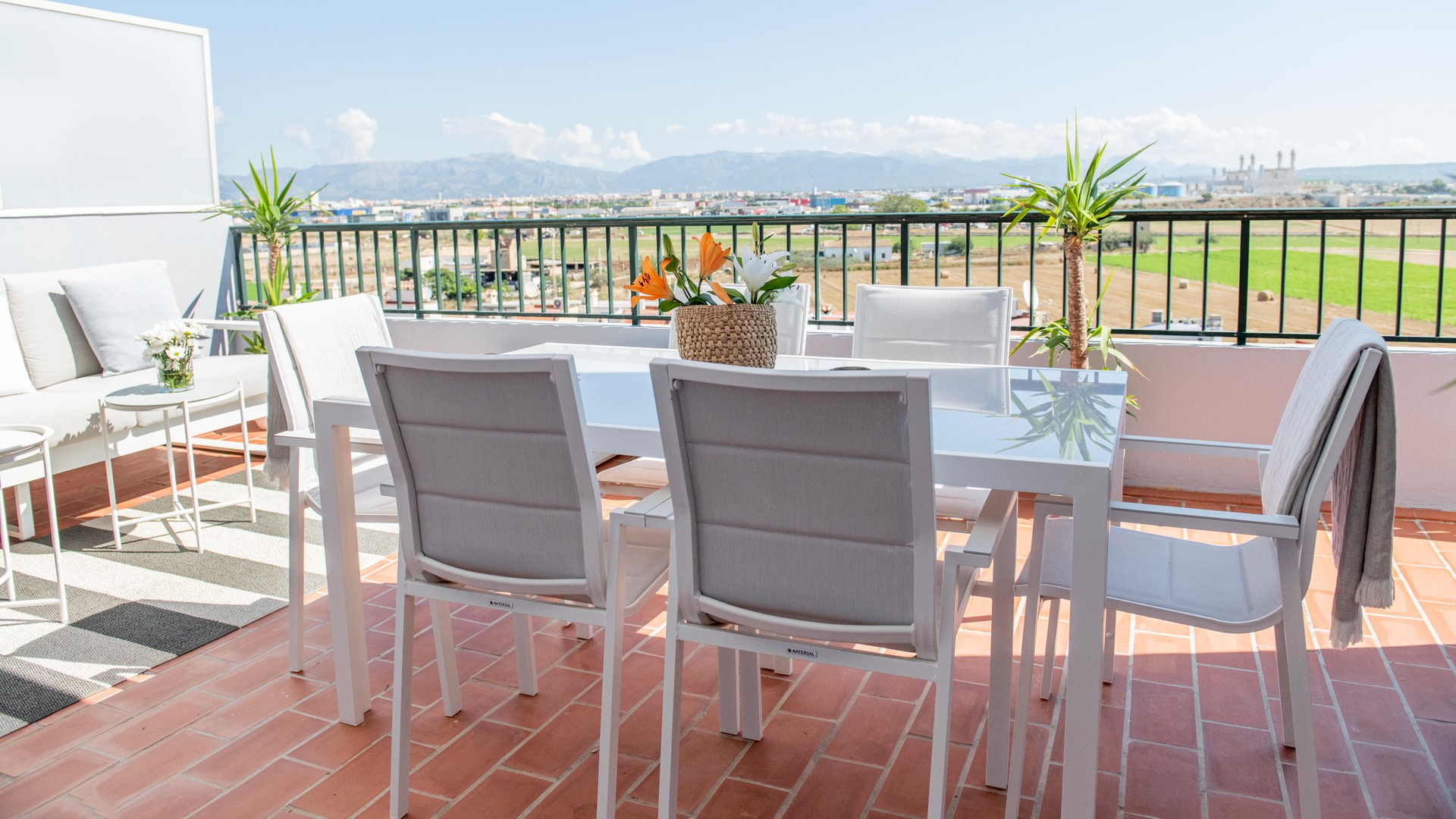 Rooftop terrace in El Molinar featuring a white dining set and outdoor sofa overlooking distant mountains under a clear sky.
