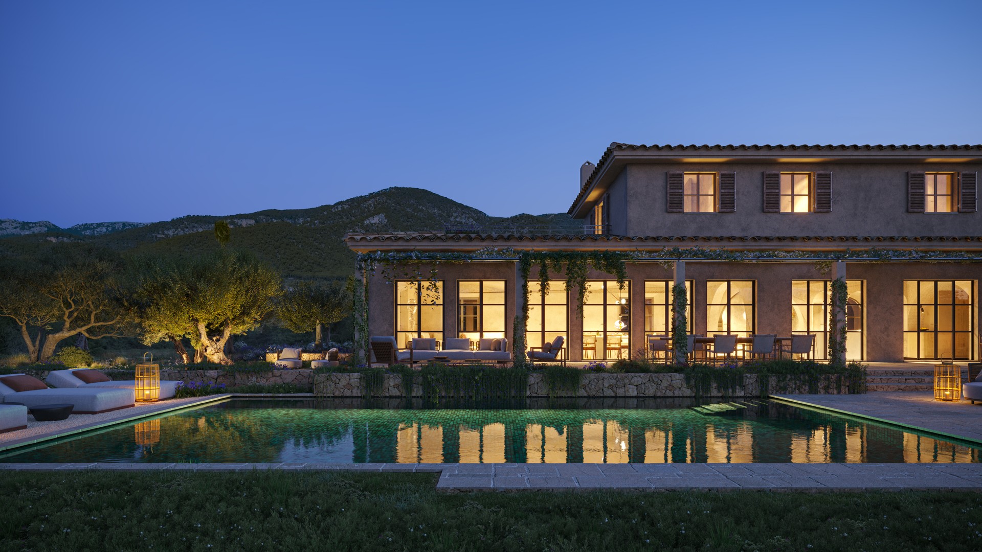 Exterior view of a stone finca at dusk, featuring a rectangular swimming pool, illuminated ground floor windows, and surrounding mountain silhouettes.