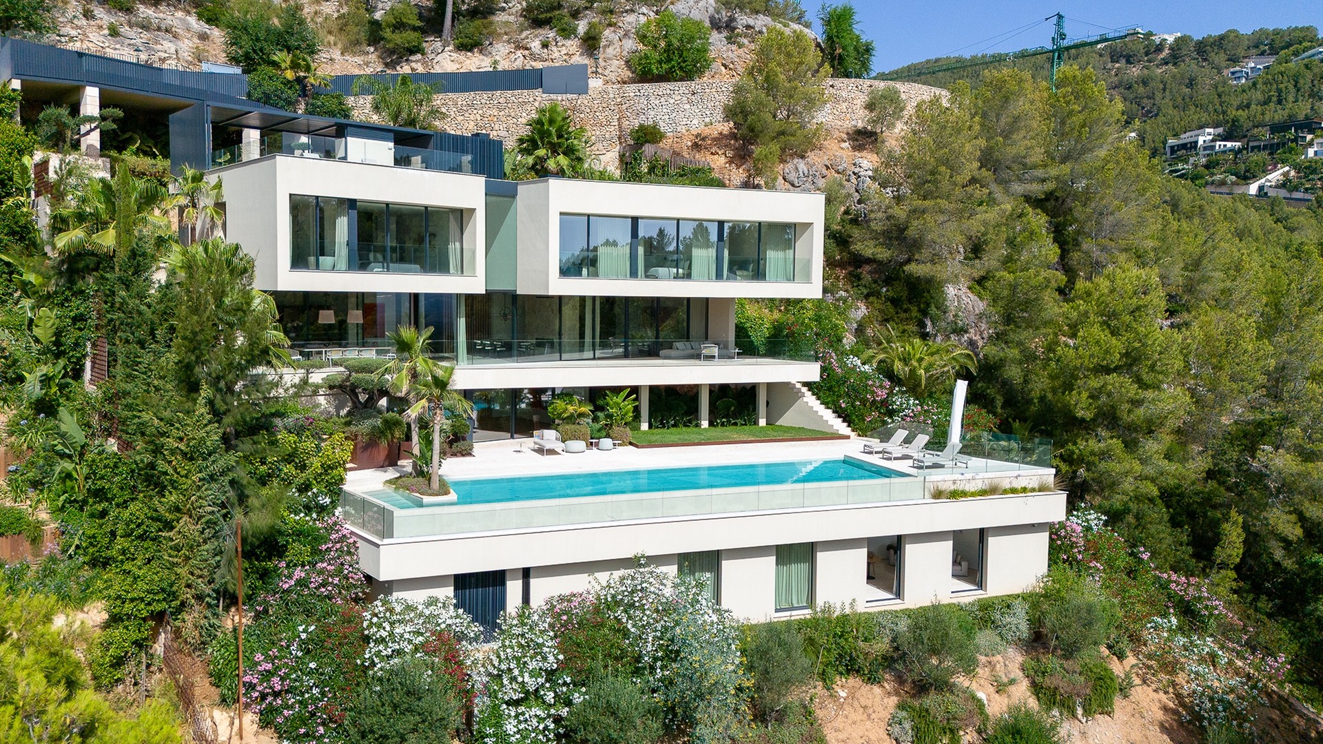 Exterior view of a multi-level contemporary villa in Son Vida, featuring a rectangular infinity pool and terraced levels.