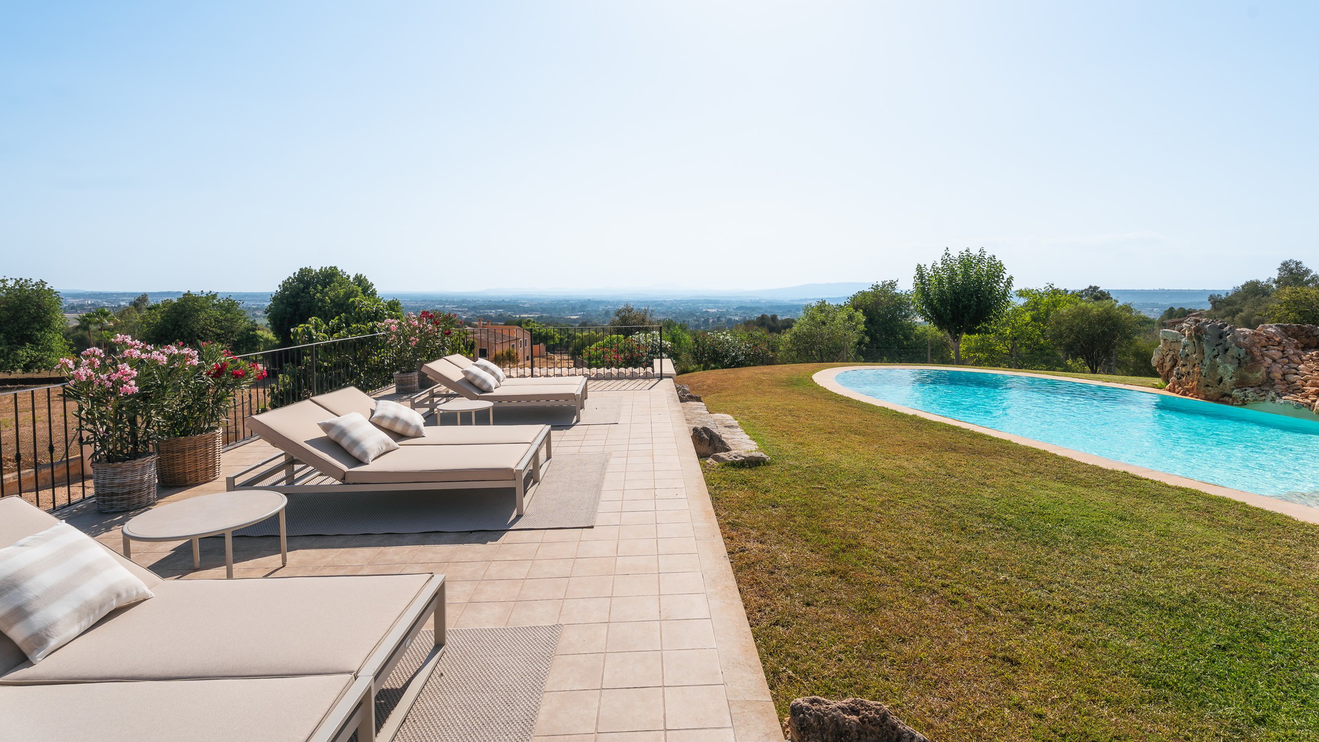 Terraza de piscina en Manacor con tumbonas sobre pavimento hacia el paisaje montañoso lejano.