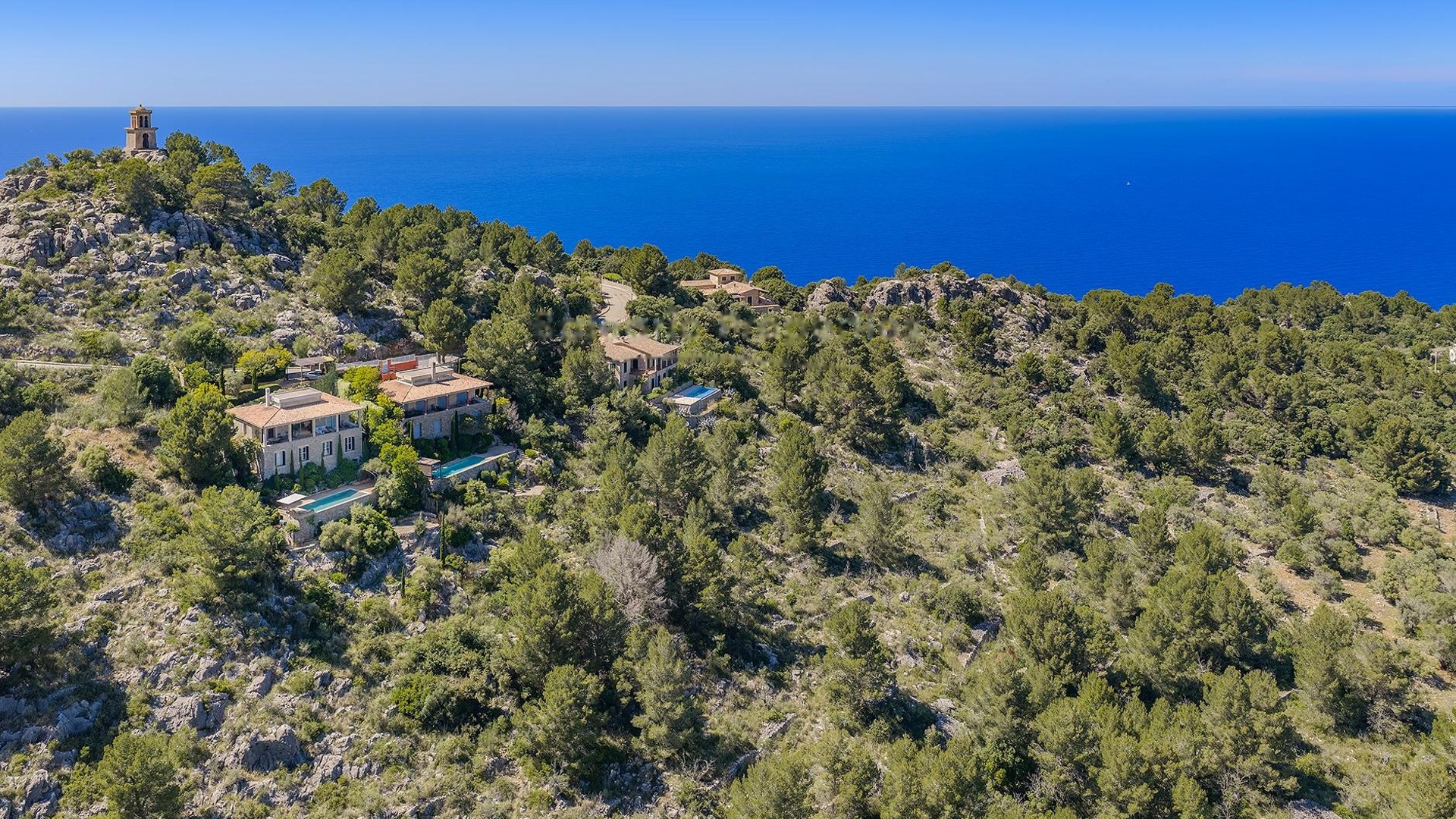 Aerial view of George Sand Villa nestled in the pine-covered hills of Valldemossa overlooking the Mediterranean Sea.