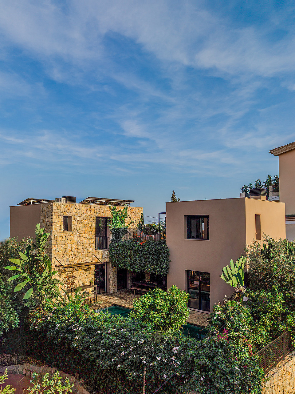 Exterior view of a multi-story villa in Genova featuring stone cladding, smooth stucco walls, and lush garden surroundings.