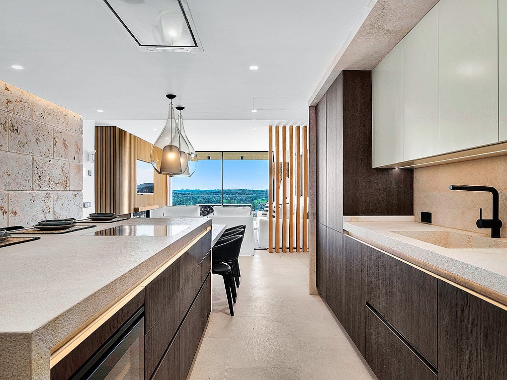 Modern kitchen with dark wood cabinetry, a stone kitchen island, and a clear view towards mountain scenery in Santa Ponsa.