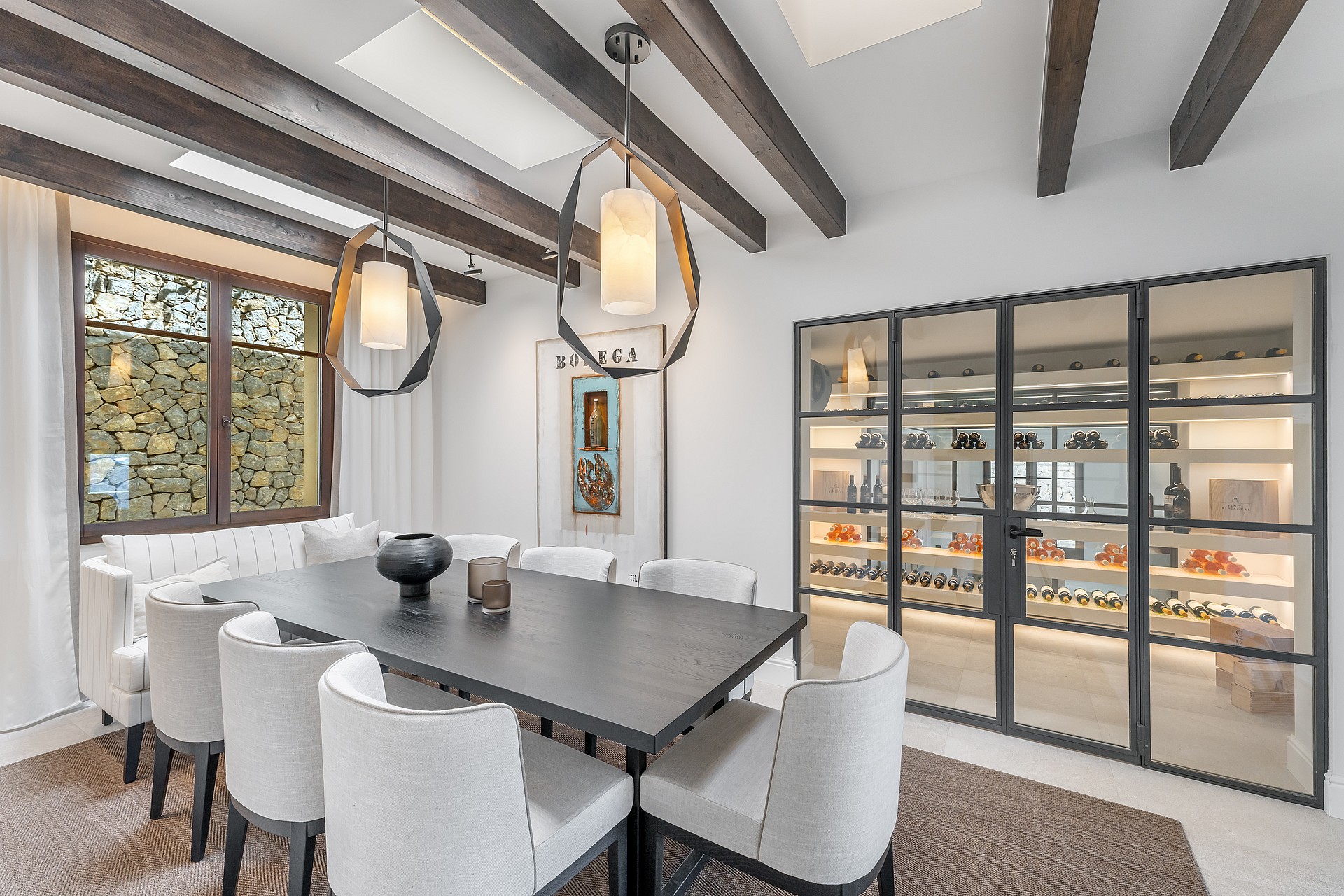 Modern dining room featuring a dark wood table, white upholstered chairs, exposed ceiling beams, and geometric pendants.