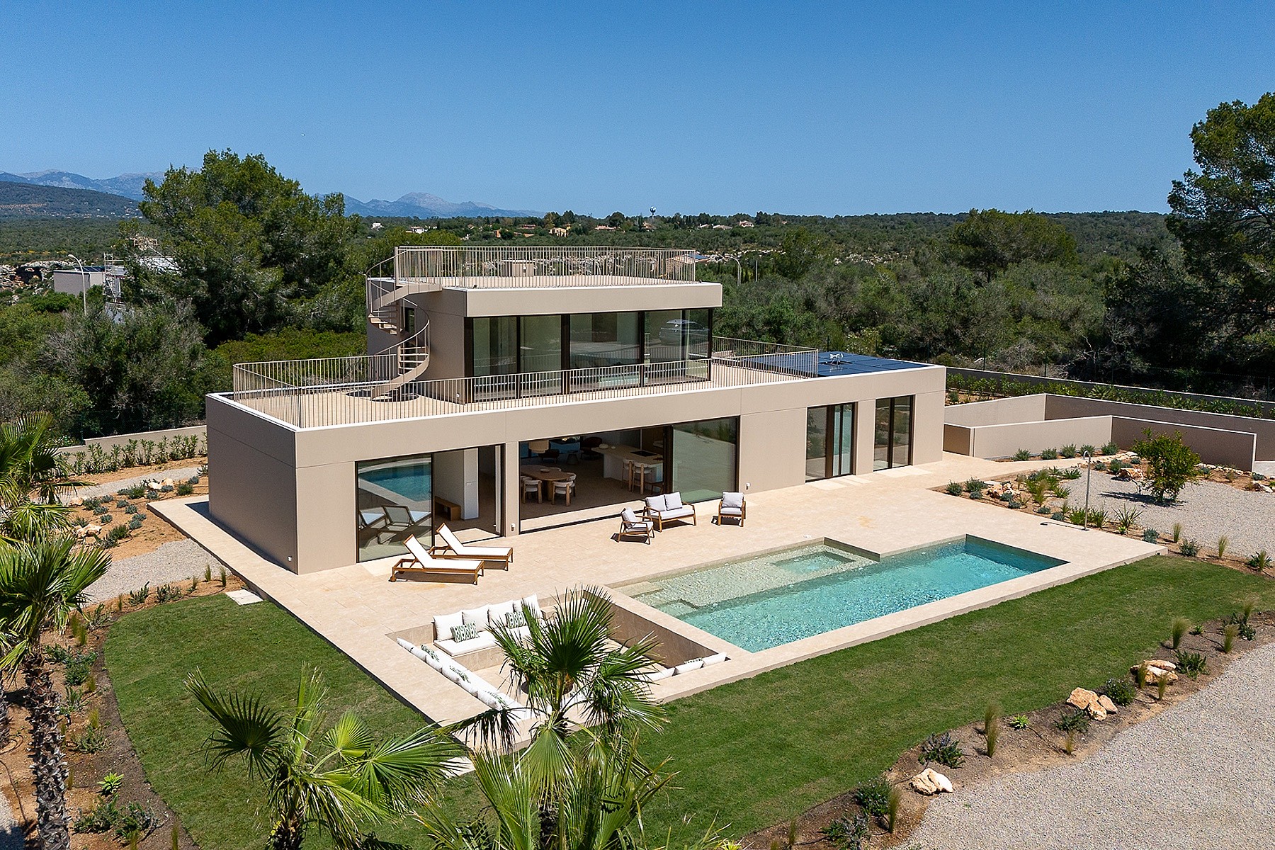 Aerial view of a modern beige villa in Son Gual featuring a rectangular swimming pool, terrace, and mountain backdrop.