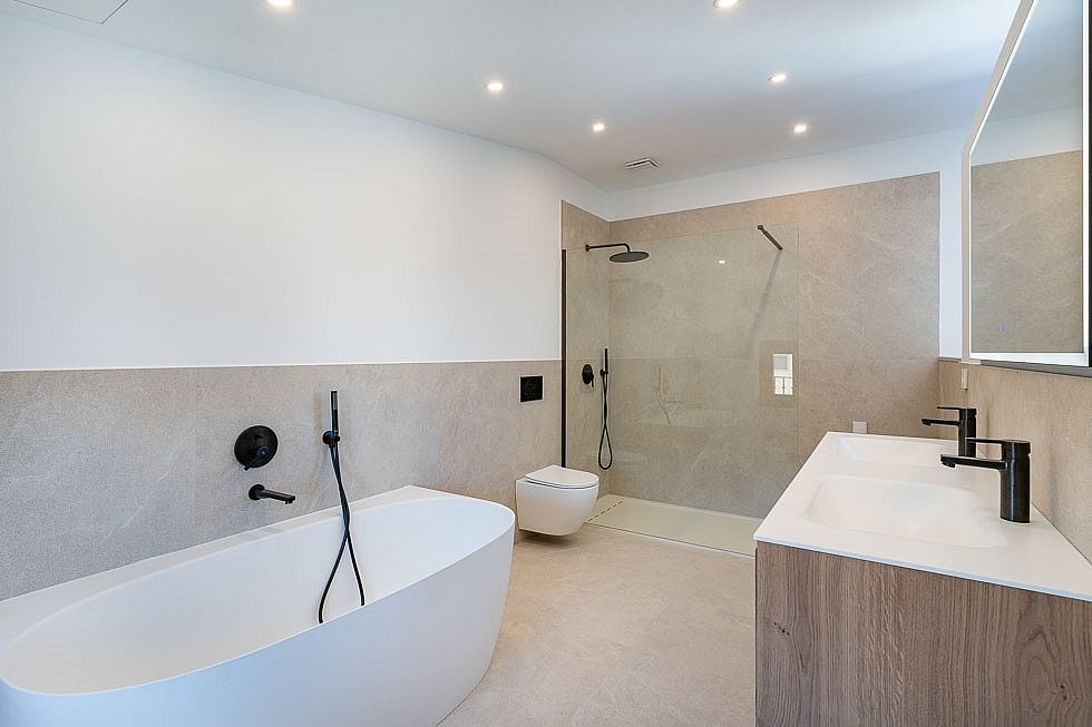 Contemporary bathroom with a white freestanding bathtub, walk-in glass shower, and wall-mounted vanity in a townhouse.