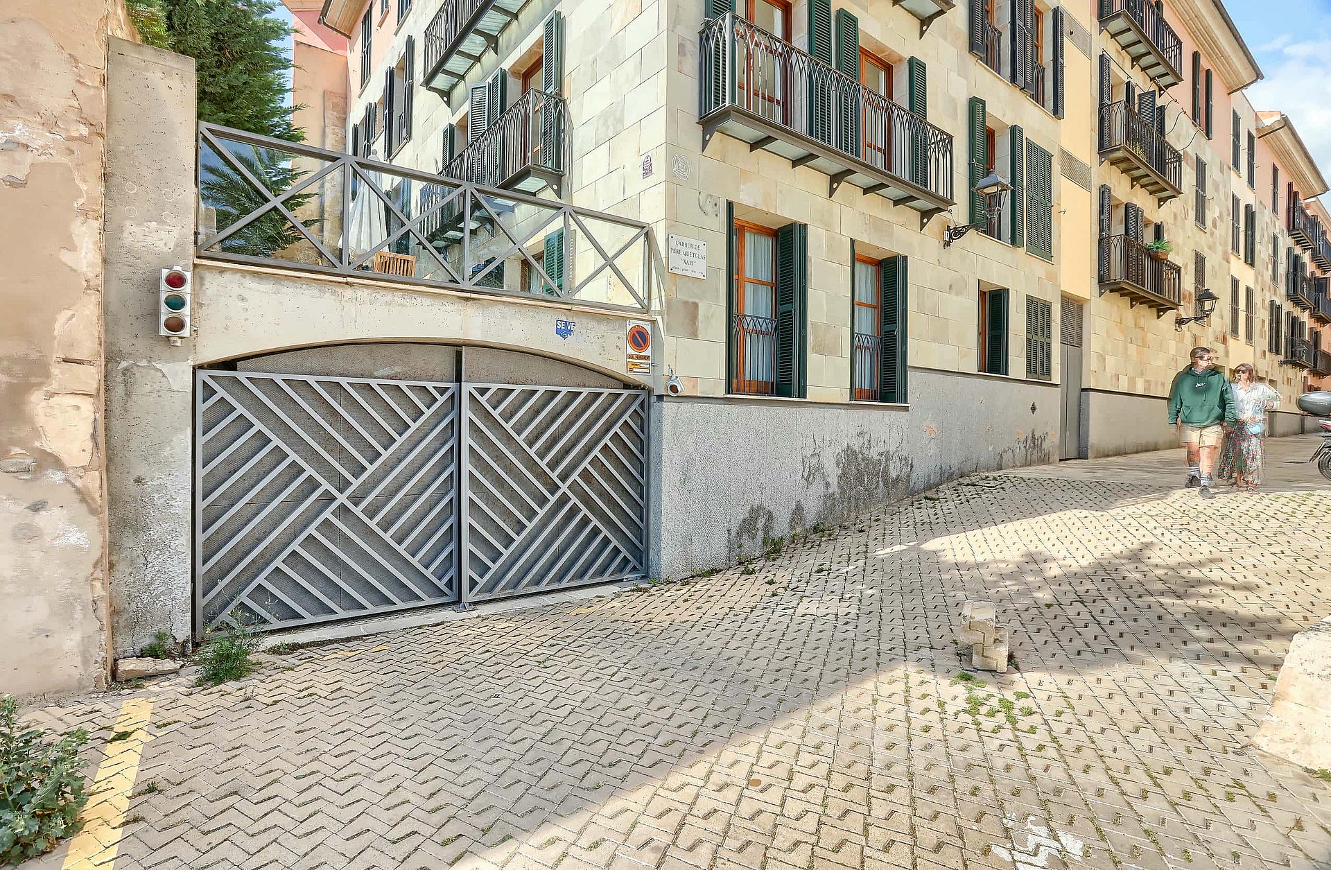 Exterior view of a residential building in the Old Town with a geometric metal garage gate and cobblestone street foreground.