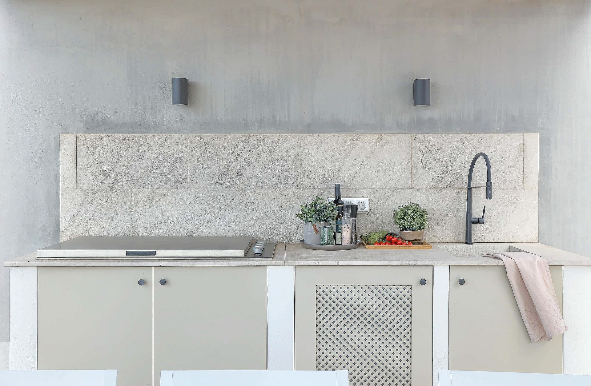 Outdoor kitchen featuring a stone backsplash, concrete wall, matte cabinetry, and a modern black faucet on a stone countertop.
