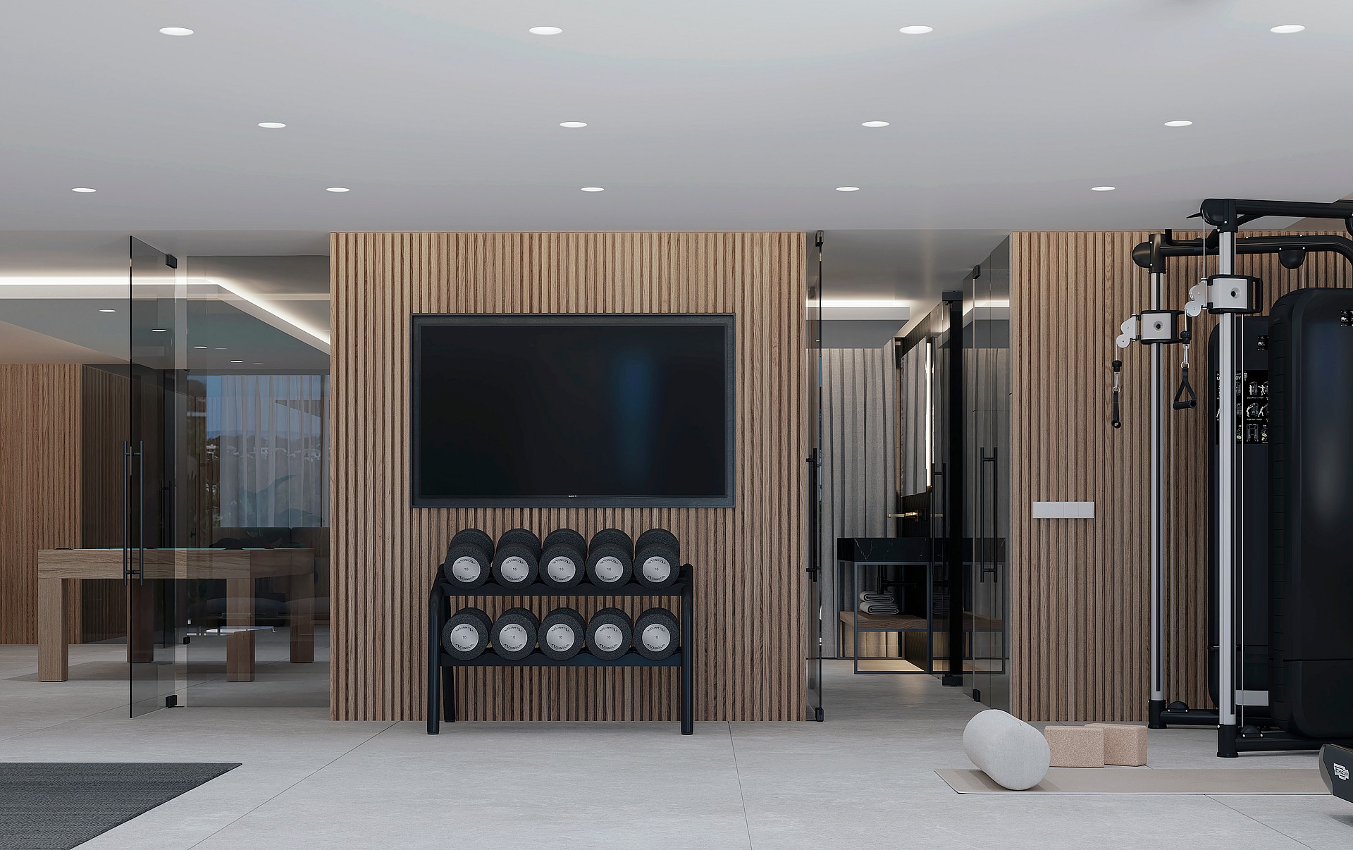 A modern home gym featuring vertical wood slat wall paneling, a rack of dumbbells, a cable pulley machine, and recessed ceiling lighting.