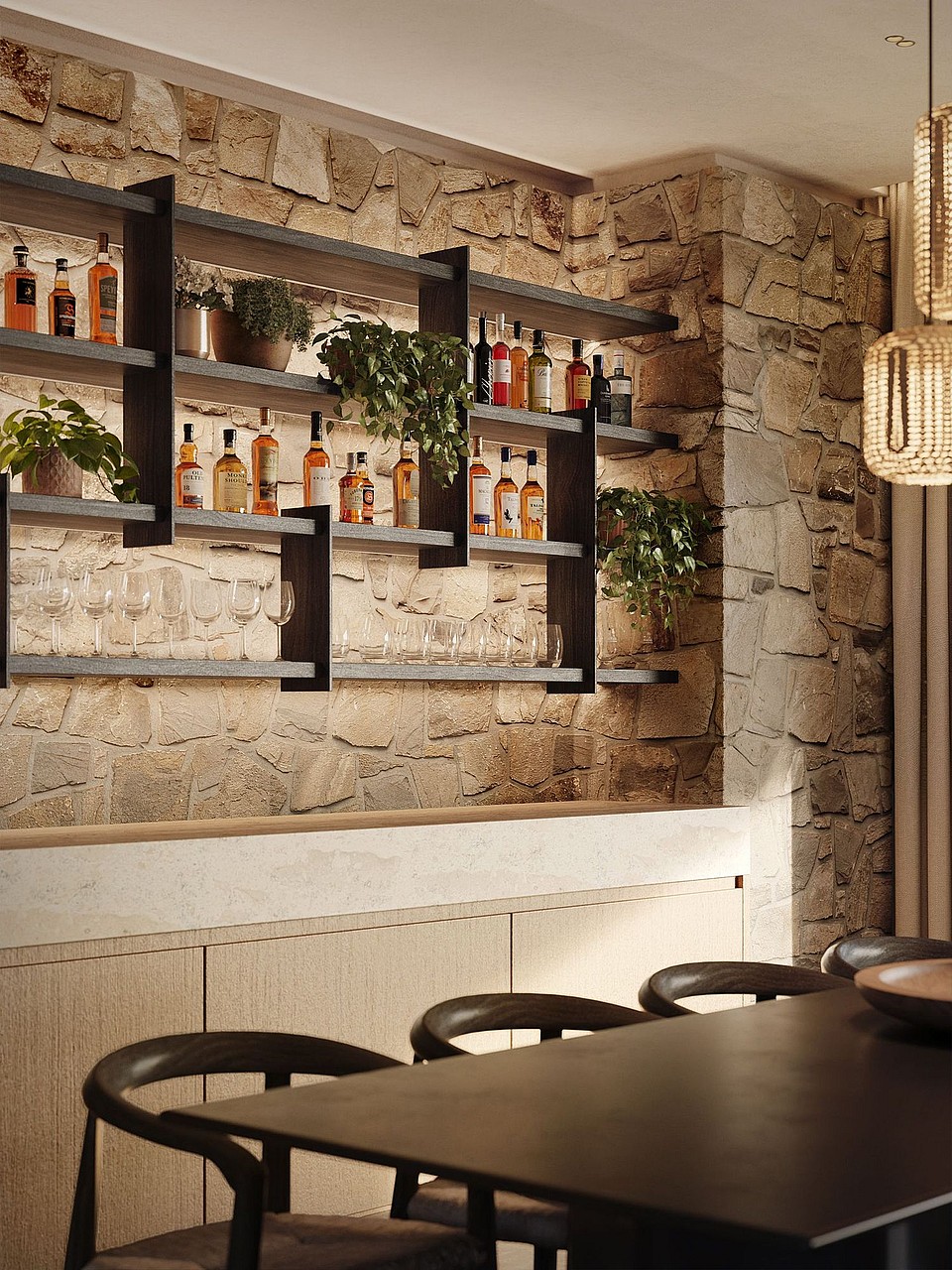 A dining space featuring a textured natural stone wall with built-in metal shelving displaying spirits and glassware above a light wood paneled bar counter.