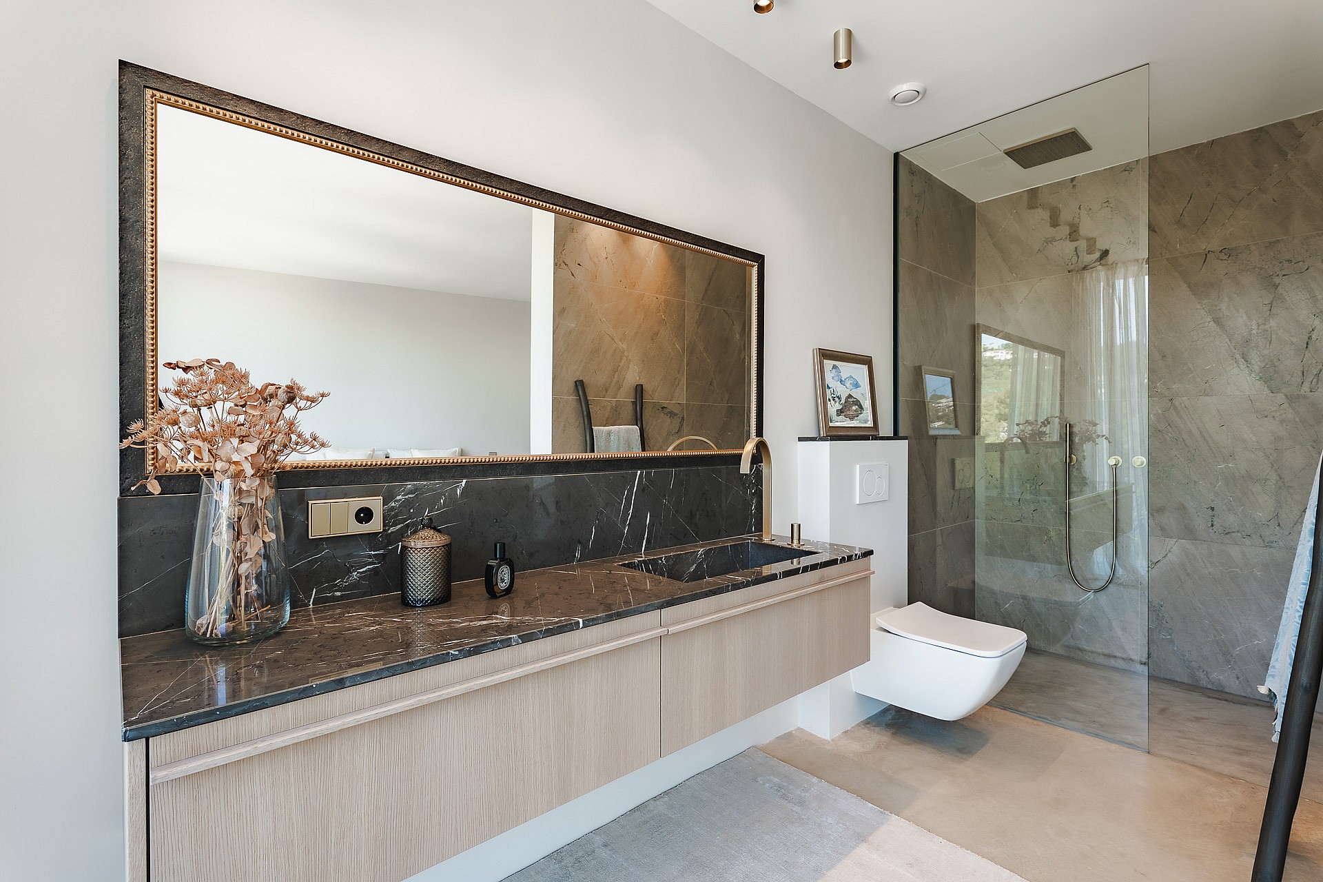 Modern bathroom featuring a floating oak vanity with a dark stone top, walk-in glass shower, and a large framed mirror.