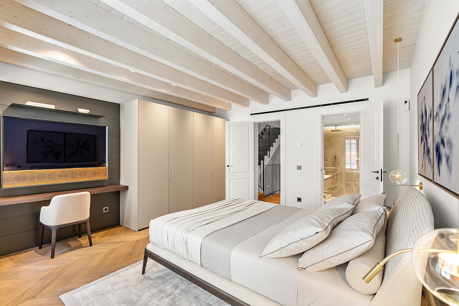 Contemporary bedroom featuring white exposed ceiling beams, chevron oak floors, built-in wardrobes, and an integrated desk.