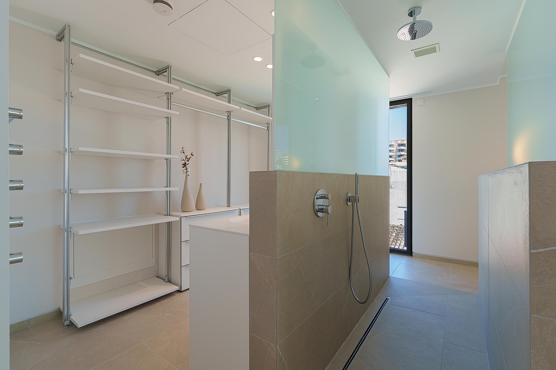 Baño moderno con ducha a ras de suelo, partición de cristal al ácido y zona de vestidor con estantes abiertos.