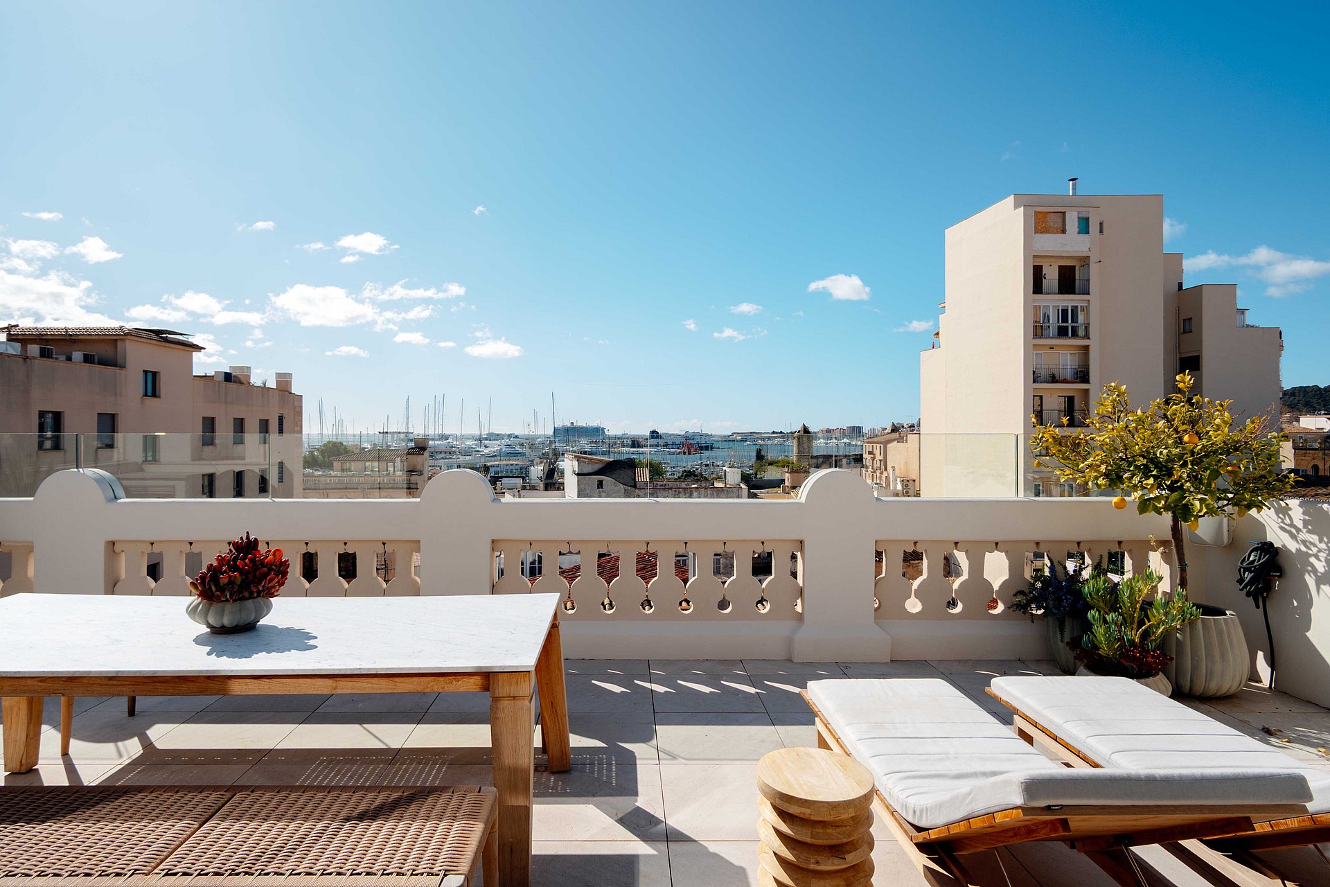 Rooftop terrace with white balustrade, dining table, and sun loungers overlooking the Santa Catalina neighborhood and port.