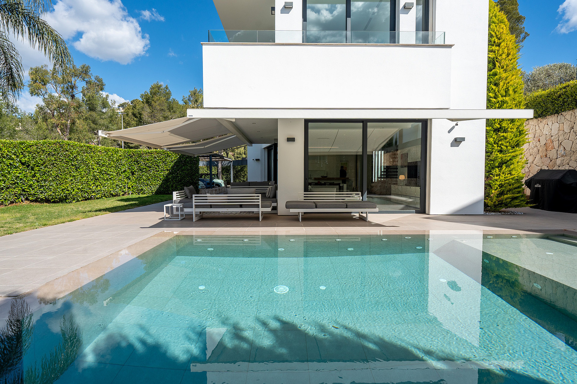 Exterior view of the villa featuring a saltwater infinity pool, covered terrace, and direct access to the living area.