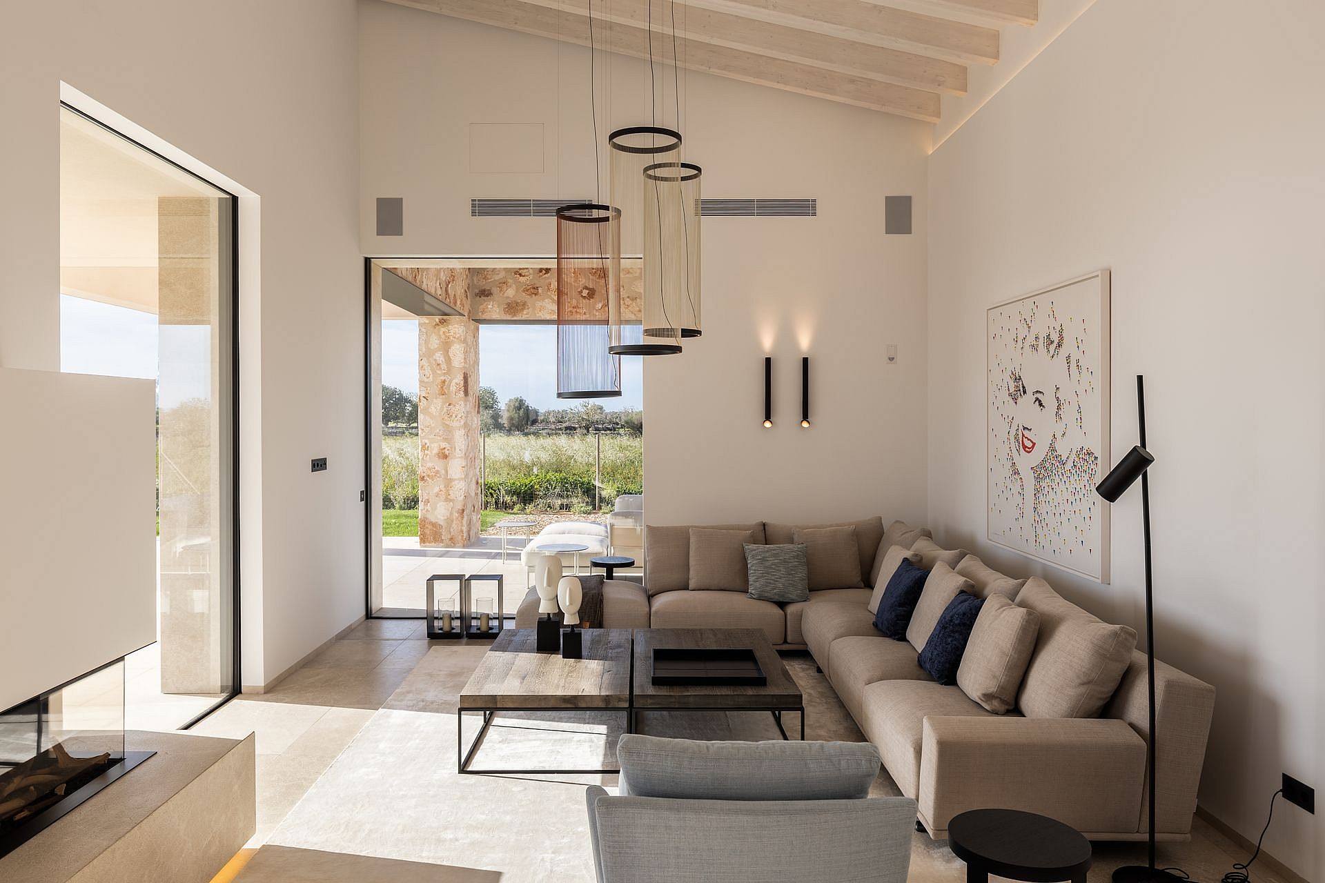 Living room with high vaulted ceiling, neutral sofa, and large glass doors opening to a terrace with mountain views.