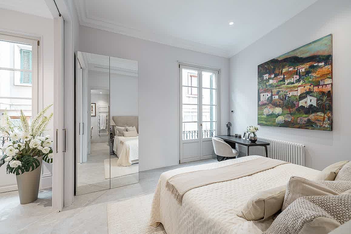Bright bedroom with a double bed, mirrored wardrobe, and a small desk near window overlooking the Old Town.