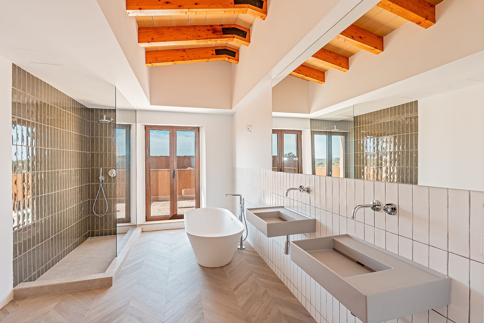 Modern bathroom featuring double concrete vanity, freestanding bathtub, walk-in shower, and exposed wood ceiling beams.