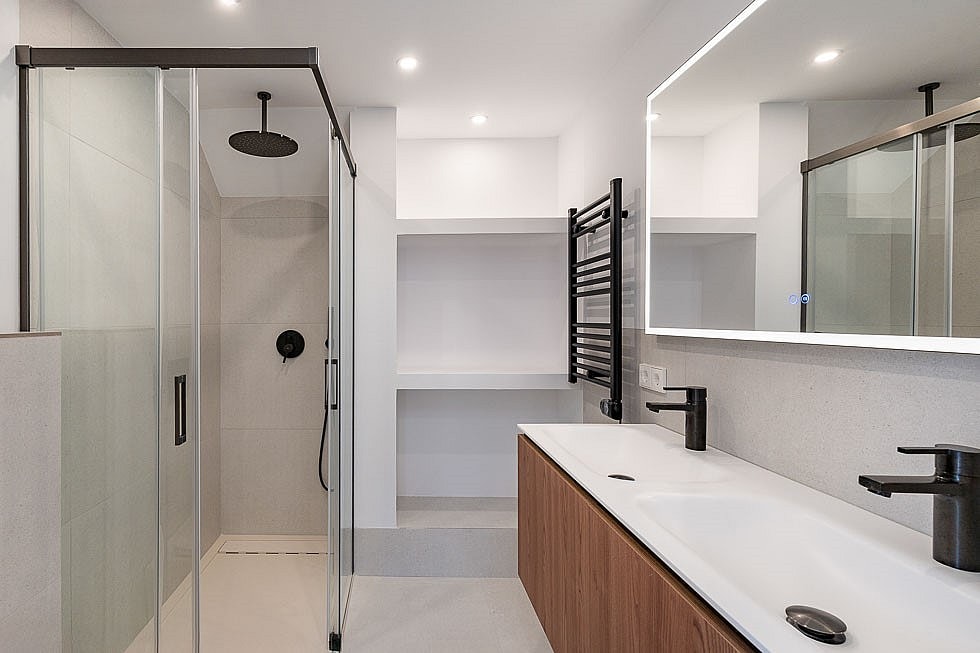 Contemporary bathroom with walk-in glass shower, wall-mounted matte black fixtures, and a wooden double vanity.