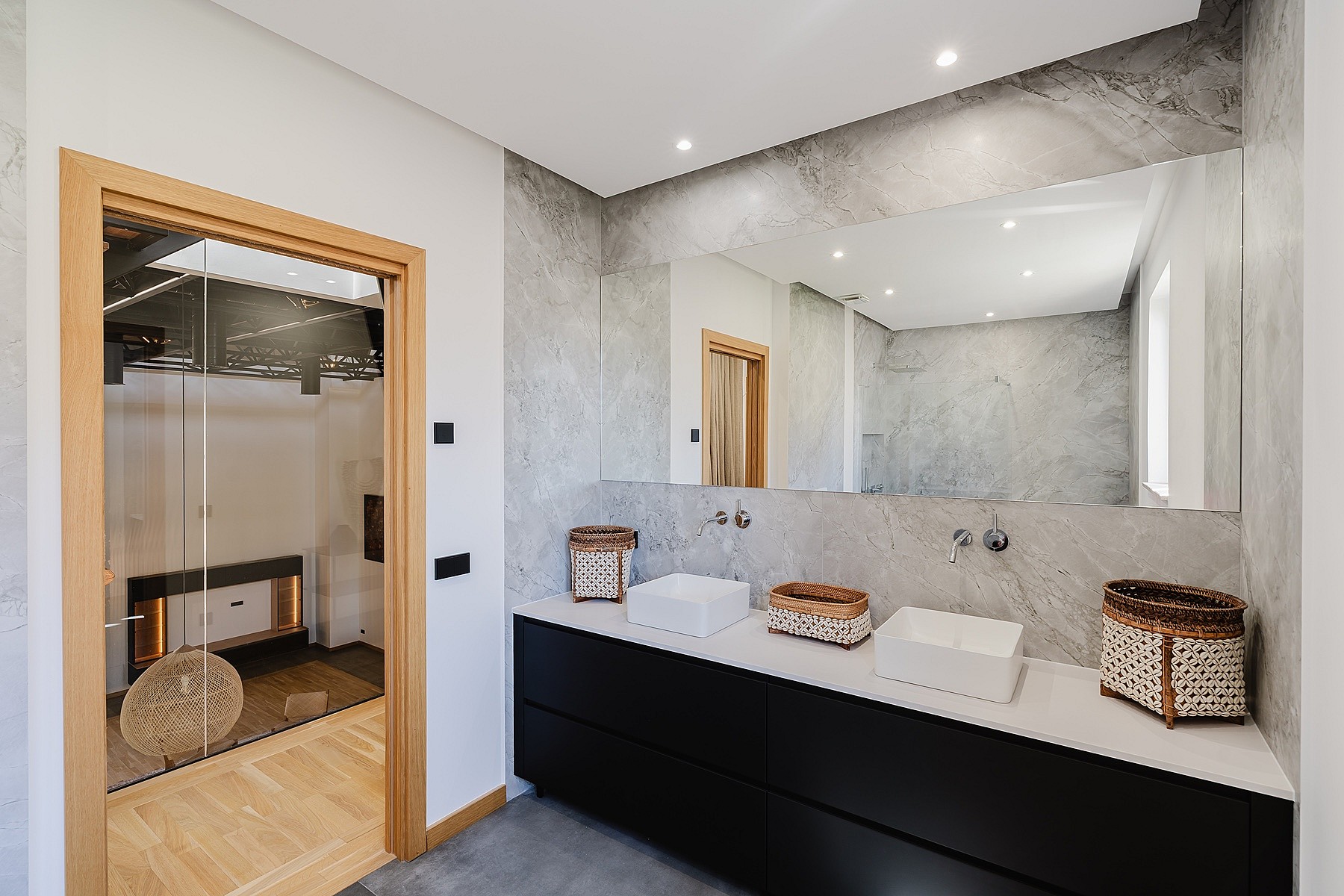 Modern bathroom featuring a black floating vanity, two white countertop sinks, a large mirror, and a glass-enclosed shower area.
