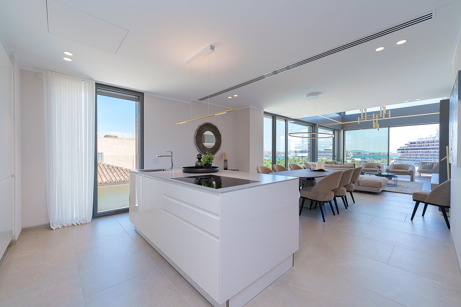 Cocina moderna con isla central blanca, suelos de baldosa clara y ventanales con acceso a la terraza.