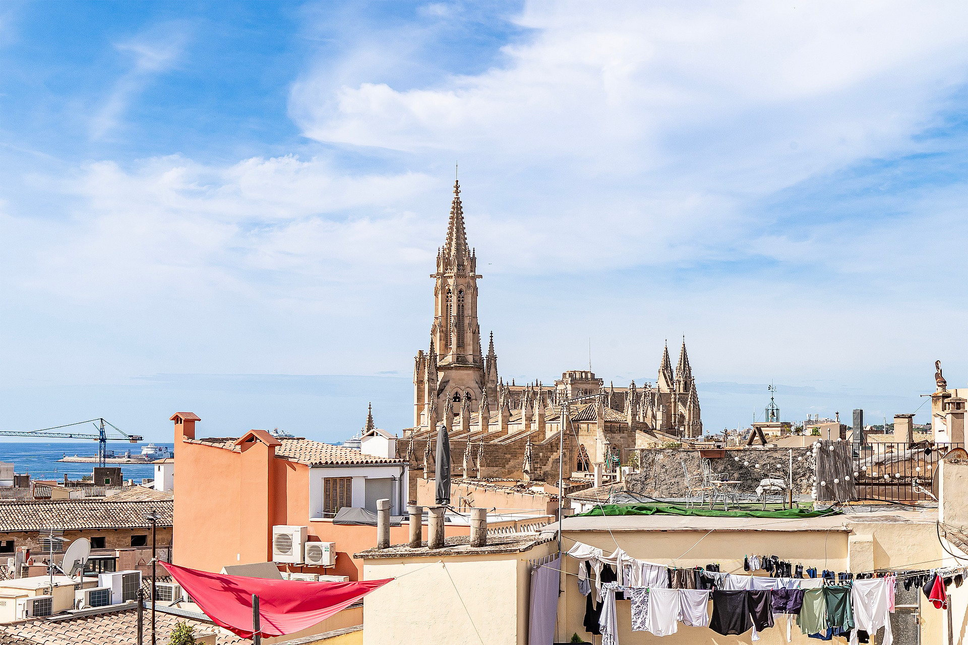 Rooftop view overlooking the city skyline, featuring a prominent historic cathedral spire under a clear blue sky.