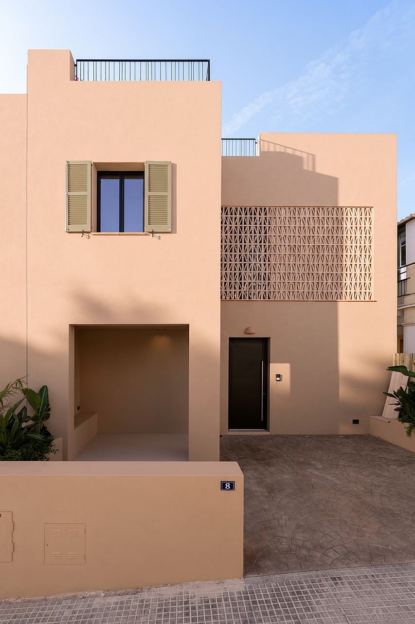 Front view of a two-story beige townhouse in Genova with geometric terracotta latticework and a covered entrance alcove.