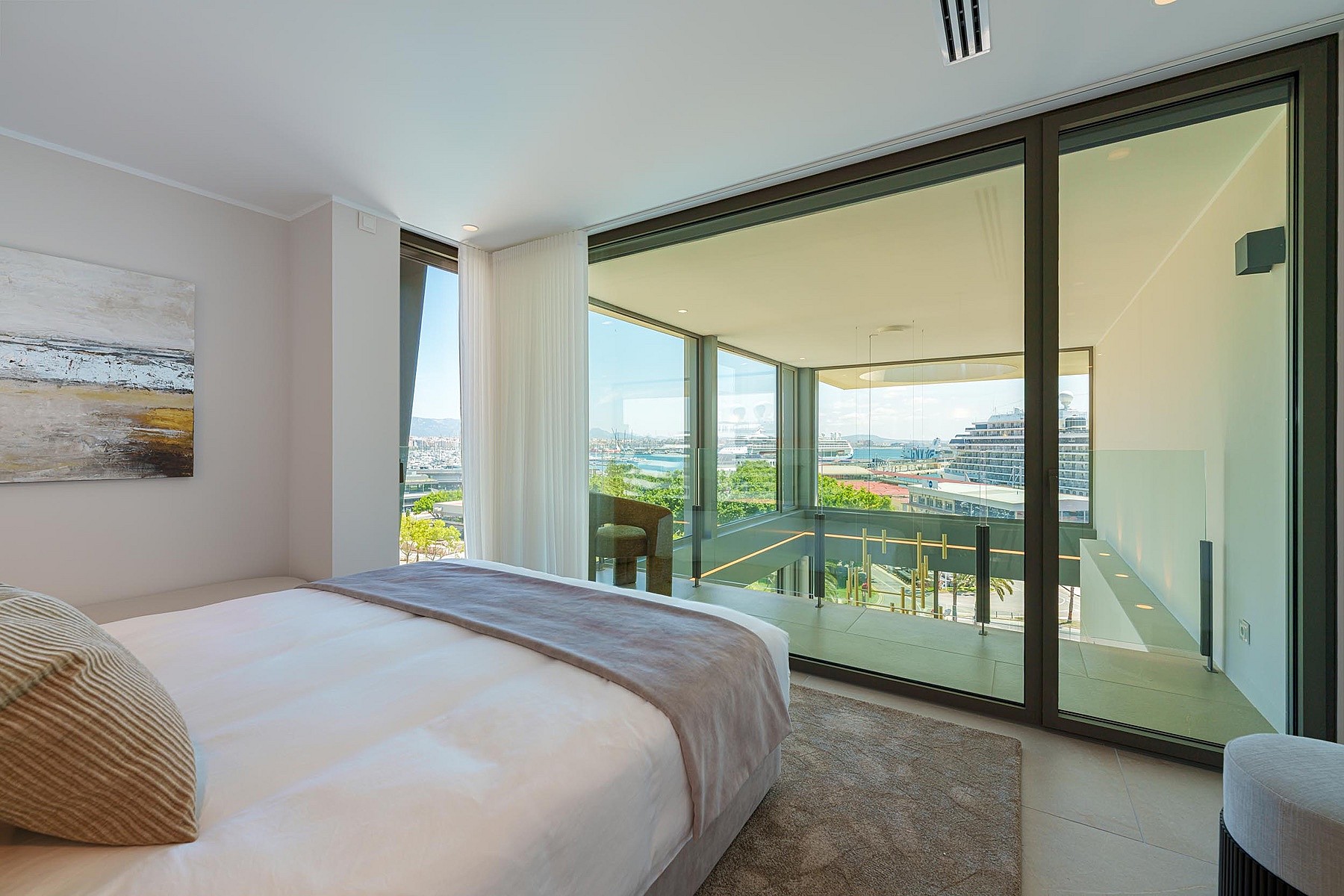 Dormitorio moderno con cama grande, decoración neutra y ventanales correderos con salida a la terraza.