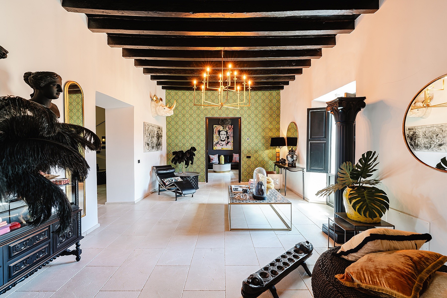 Spacious living room featuring dark exposed wooden ceiling beams, white walls, and decorative green wallpaper in a Sencelles property.