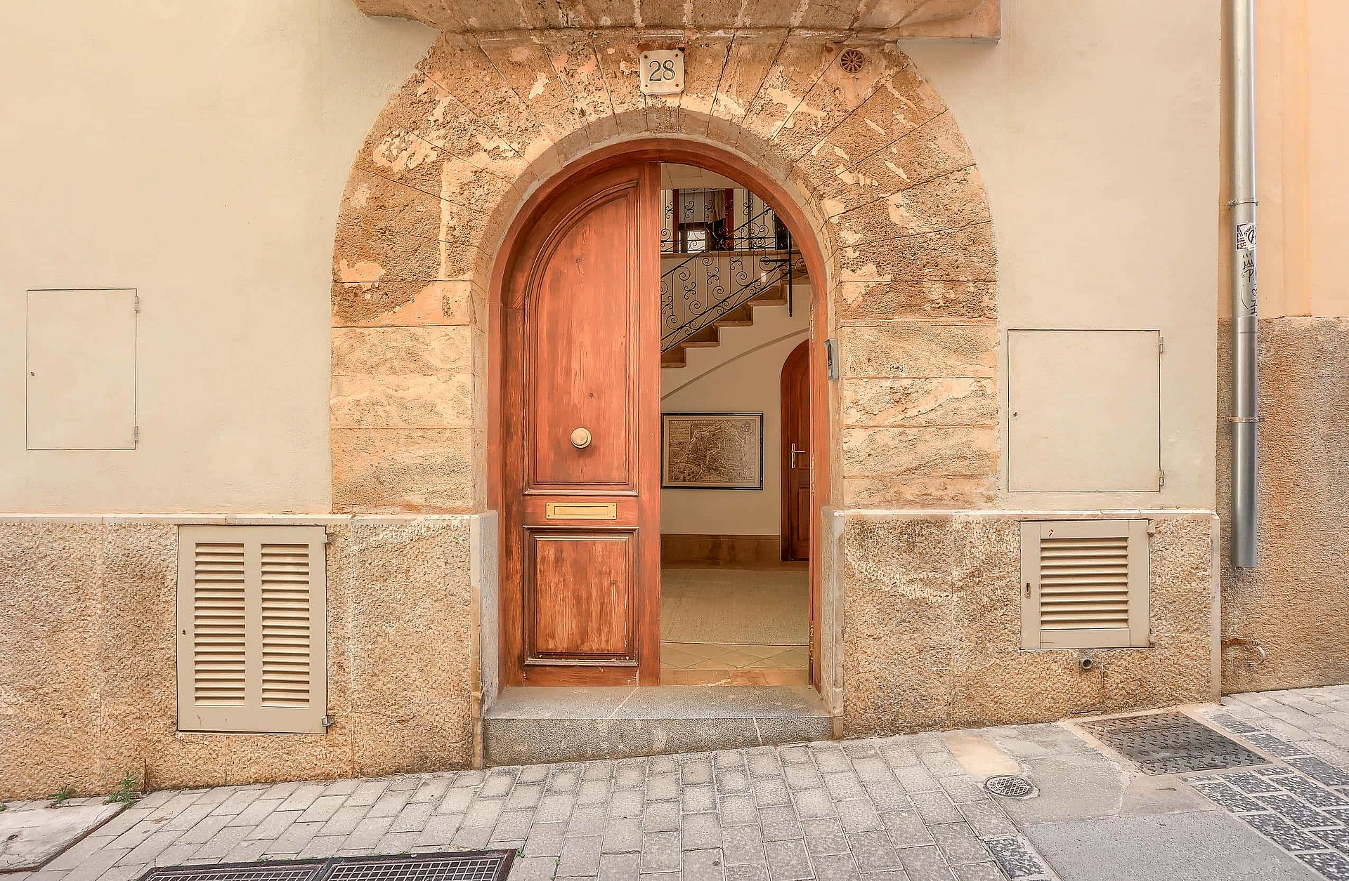 An arched timber front door set within a traditional natural stone facade on a cobblestone Old Town street.