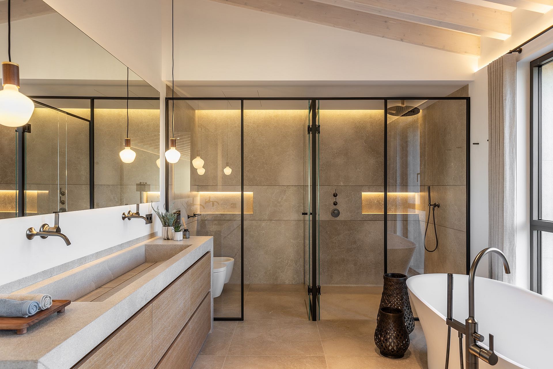 Modern bathroom featuring a double vanity with stone basin, a walk-in glass shower, and a freestanding white bathtub.
