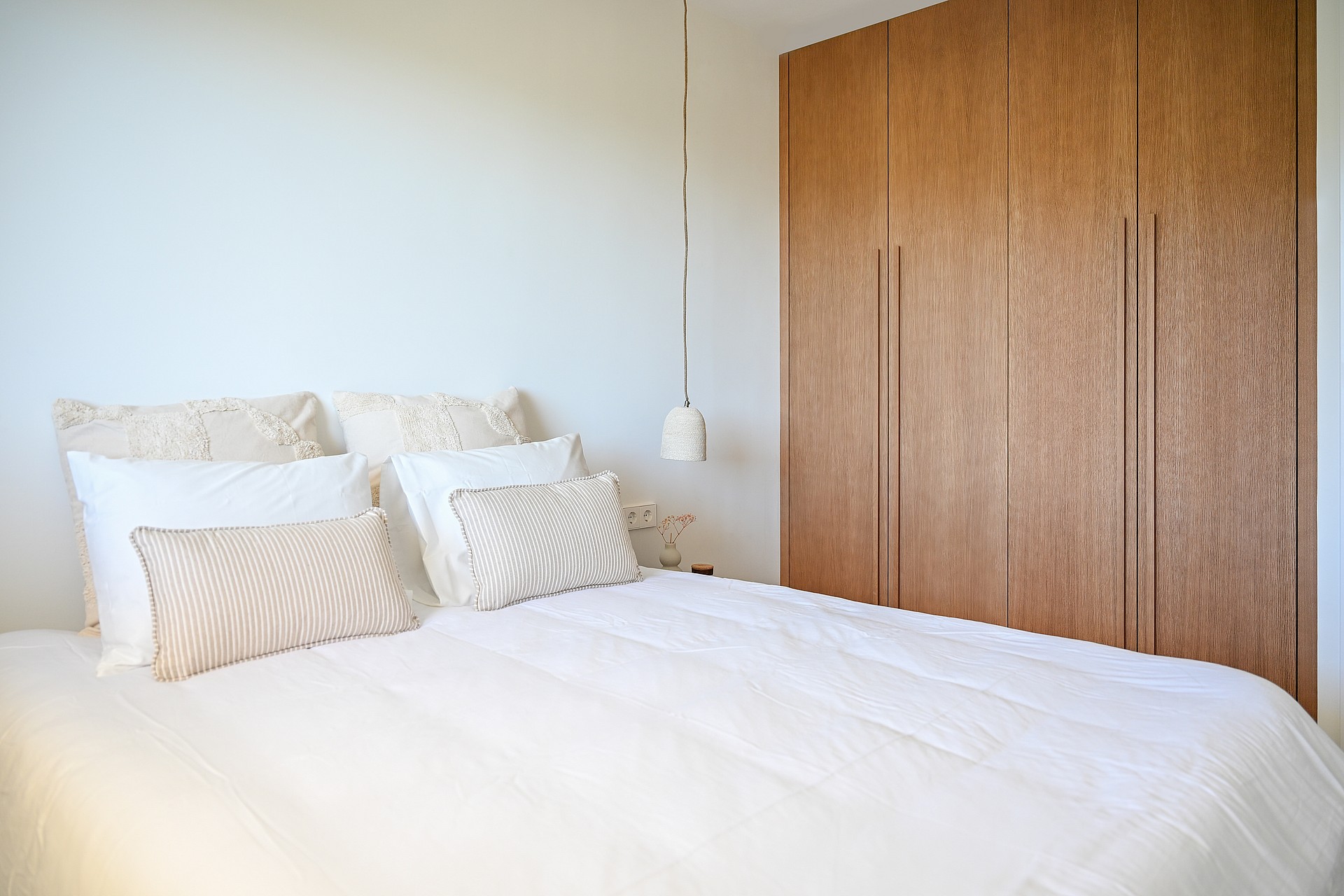 Guest bedroom with caramel linen bedding, oak low shelving beneath eaves, and minimalist Nordic styling