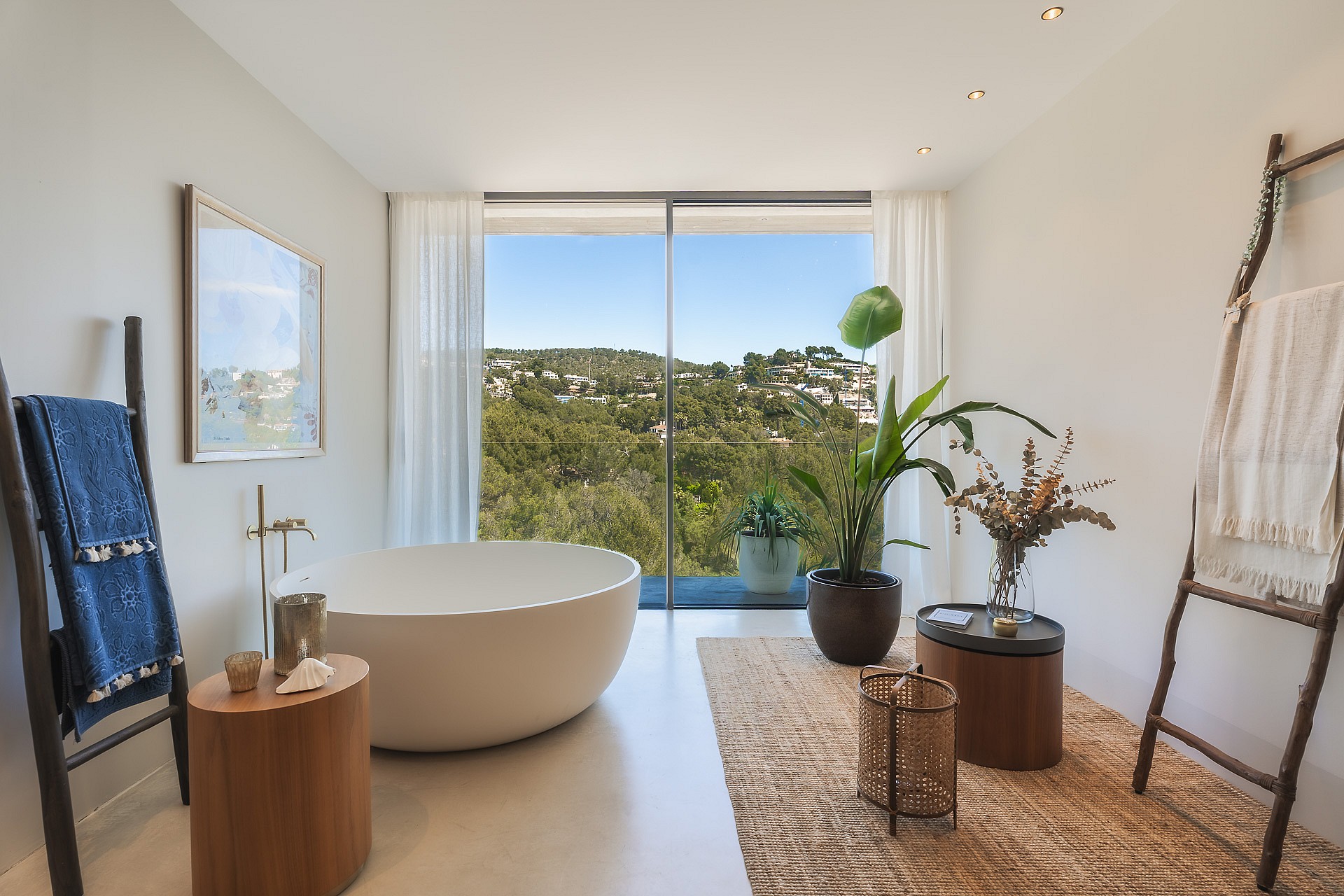 A white freestanding bathtub positioned beside floor-to-ceiling windows with views of the Son Vida landscape.
