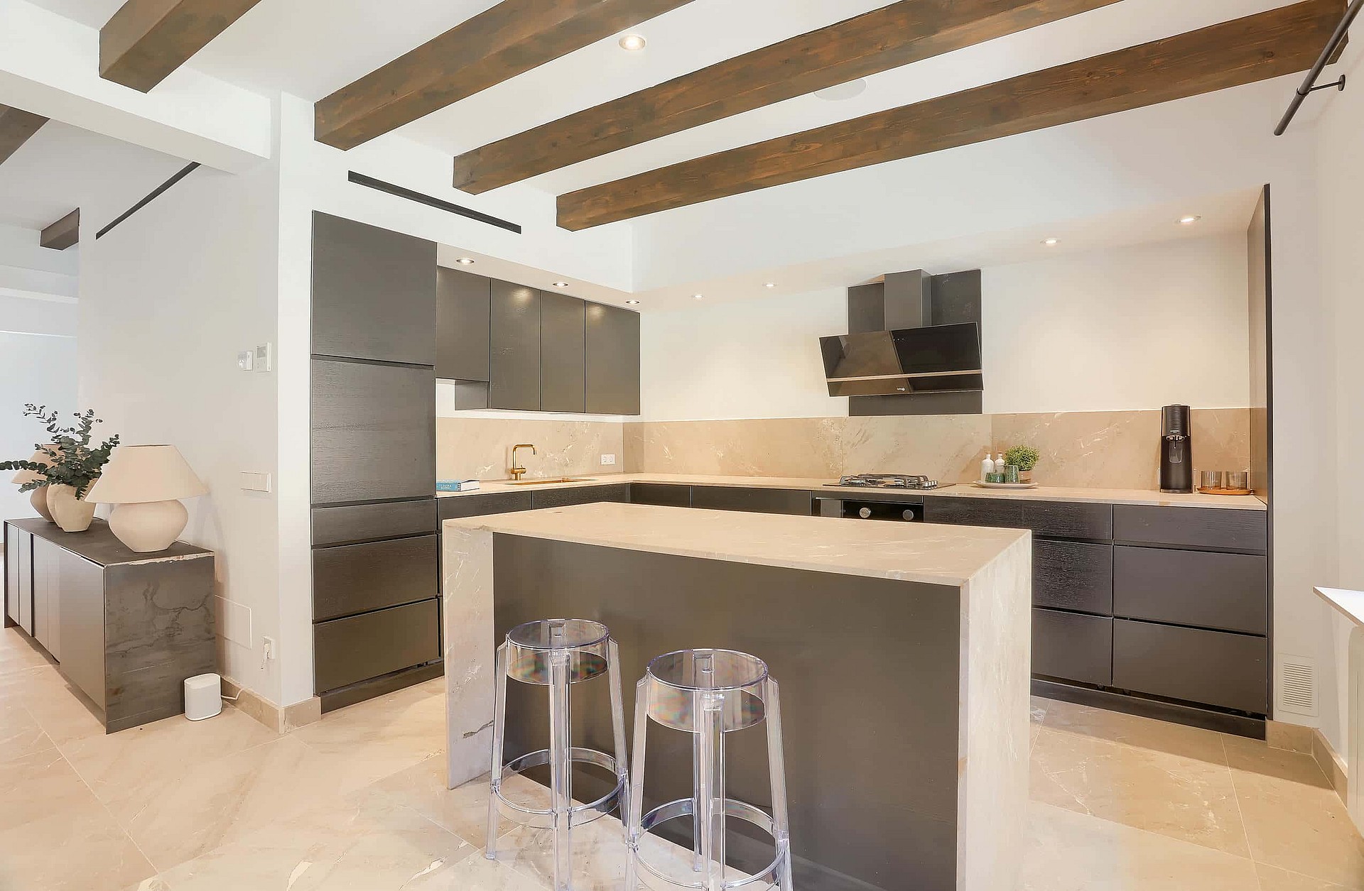 Modern kitchen with dark grey cabinetry, central stone island, and exposed timber ceiling beams in an Old Town townhouse.