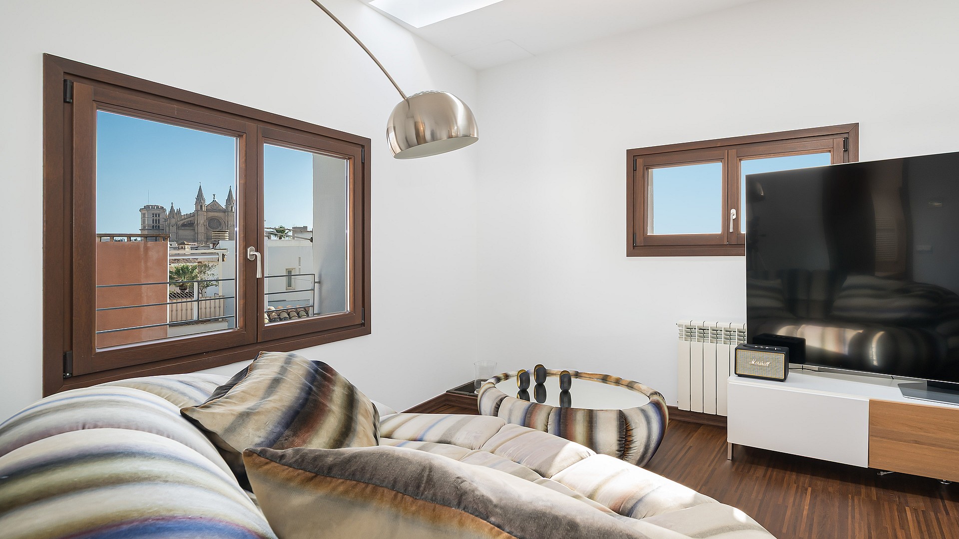Modern living room with dark wood floors, skylight, and windows framing the Palma Cathedral.