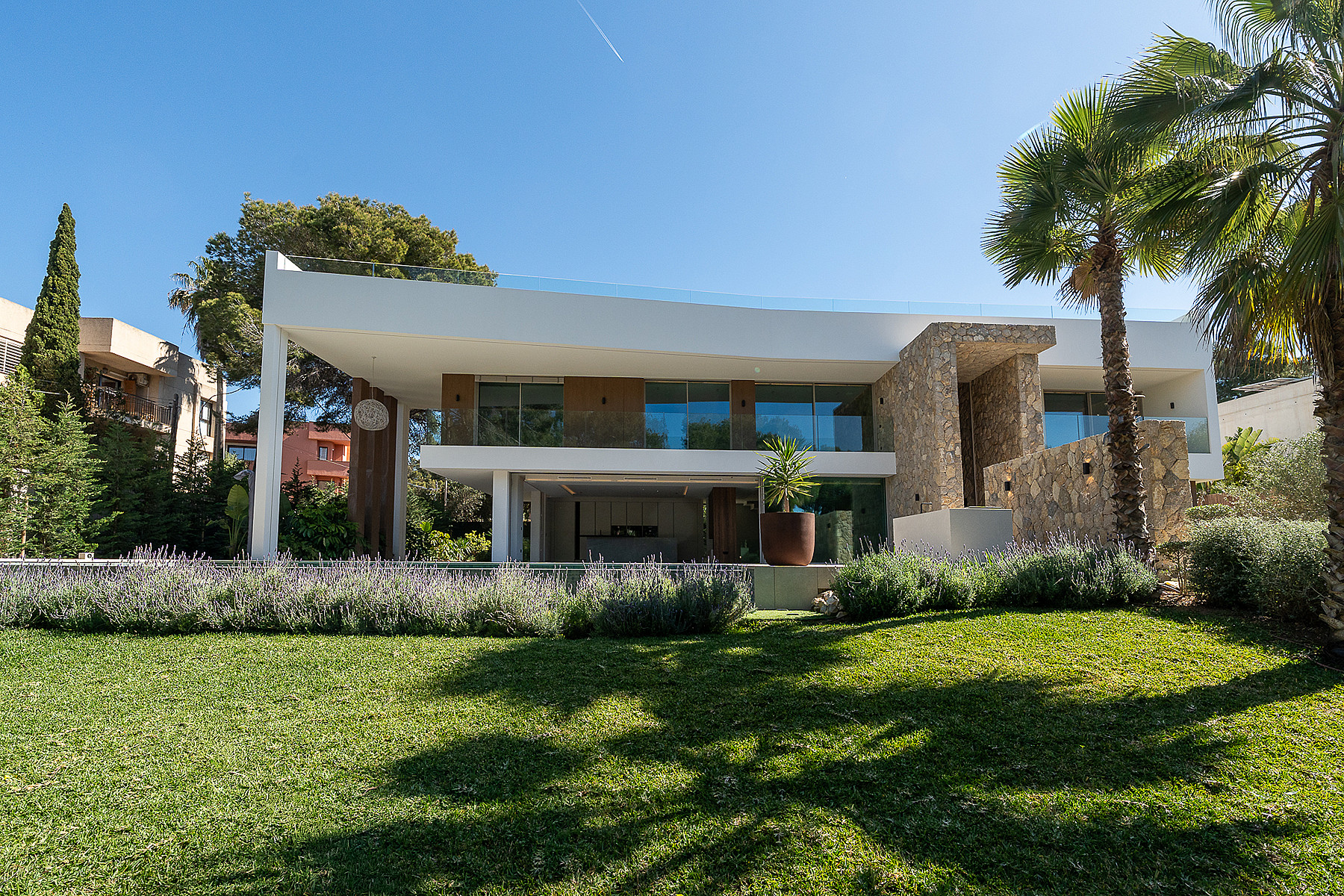 Exterior view of a modern two-story villa in Santa Ponsa, featuring stone walls, glass balconies, and a manicured garden.