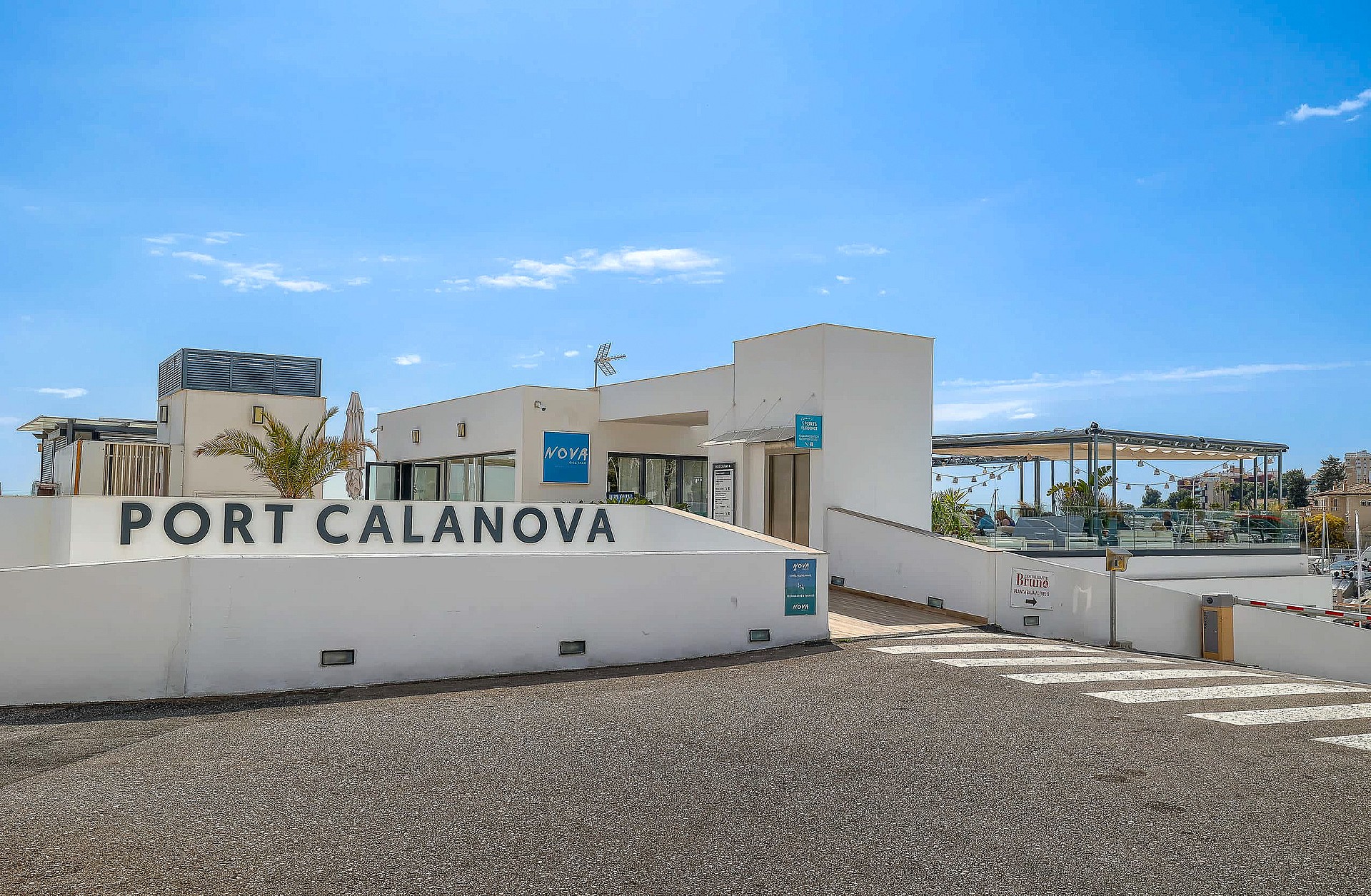 Exterior view of the white facade and entrance signage for Port Calanova under a clear blue sky.