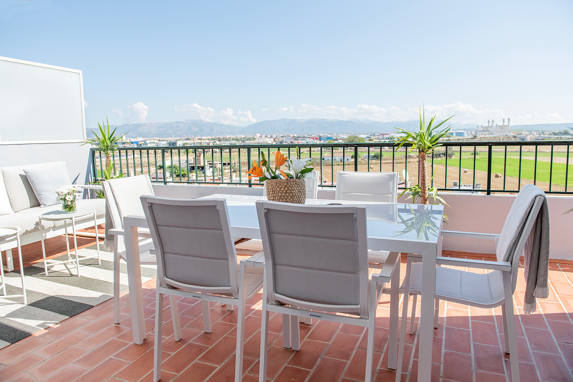 Rooftop terrace in El Molinar featuring a white dining set and outdoor sofa overlooking distant mountains under a clear sky.