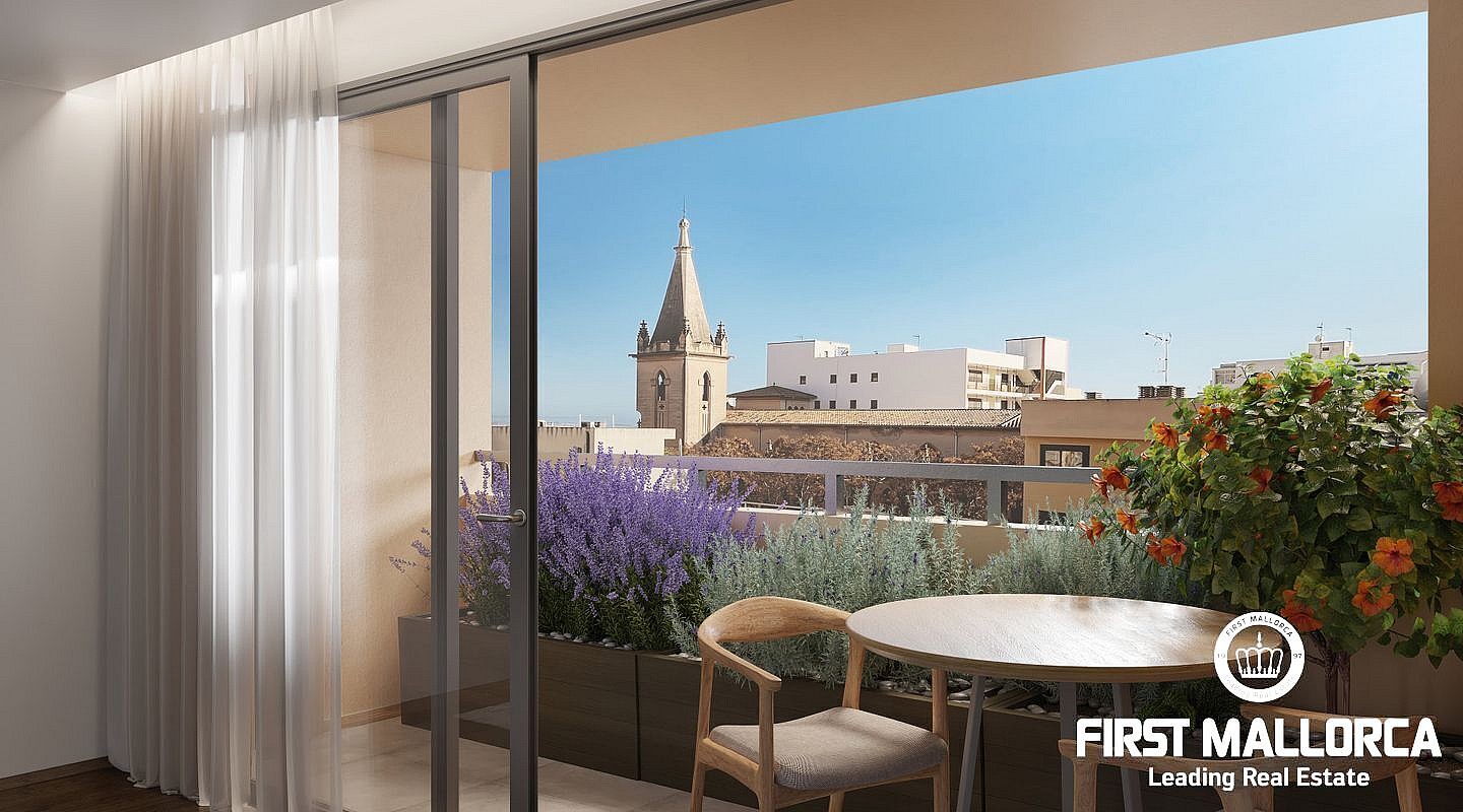 A modern apartment terrace featuring a small wooden table and chair, looking out over the Santa Catalina cityscape under a clear blue sky.