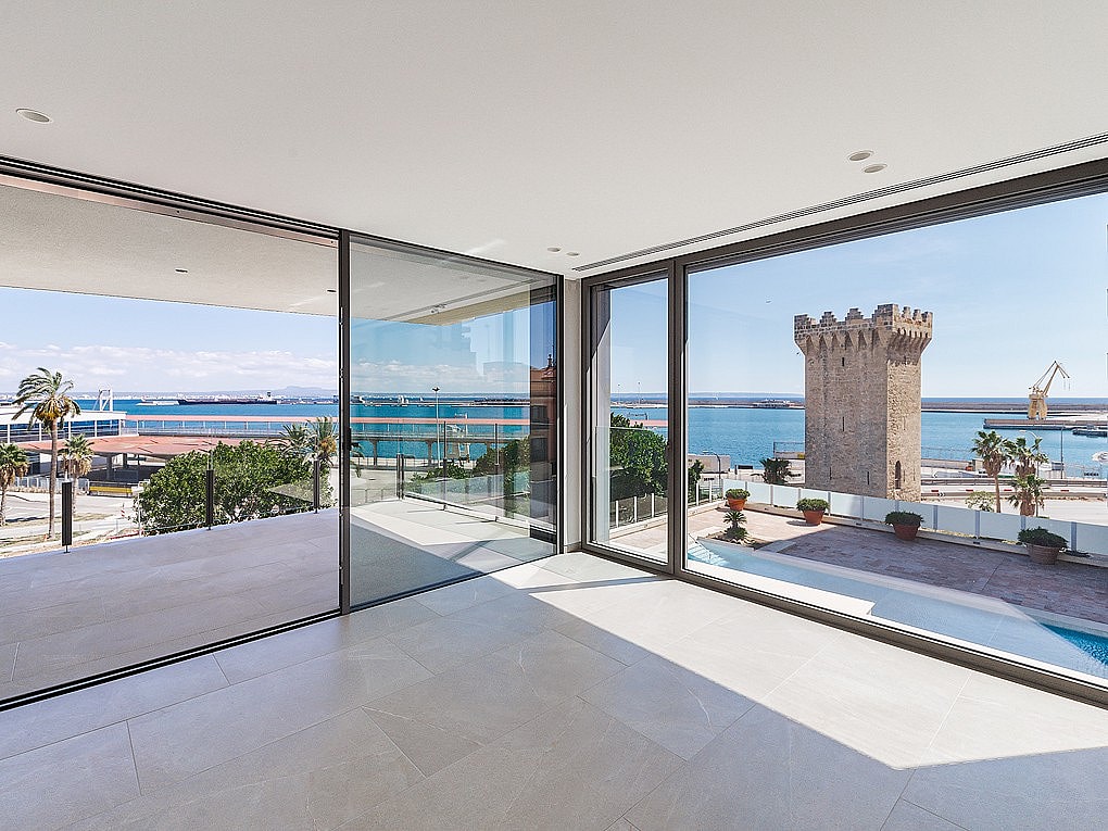 Light-filled corner living space with floor-to-ceiling glass on two elevations framing Palma harbour and open sea