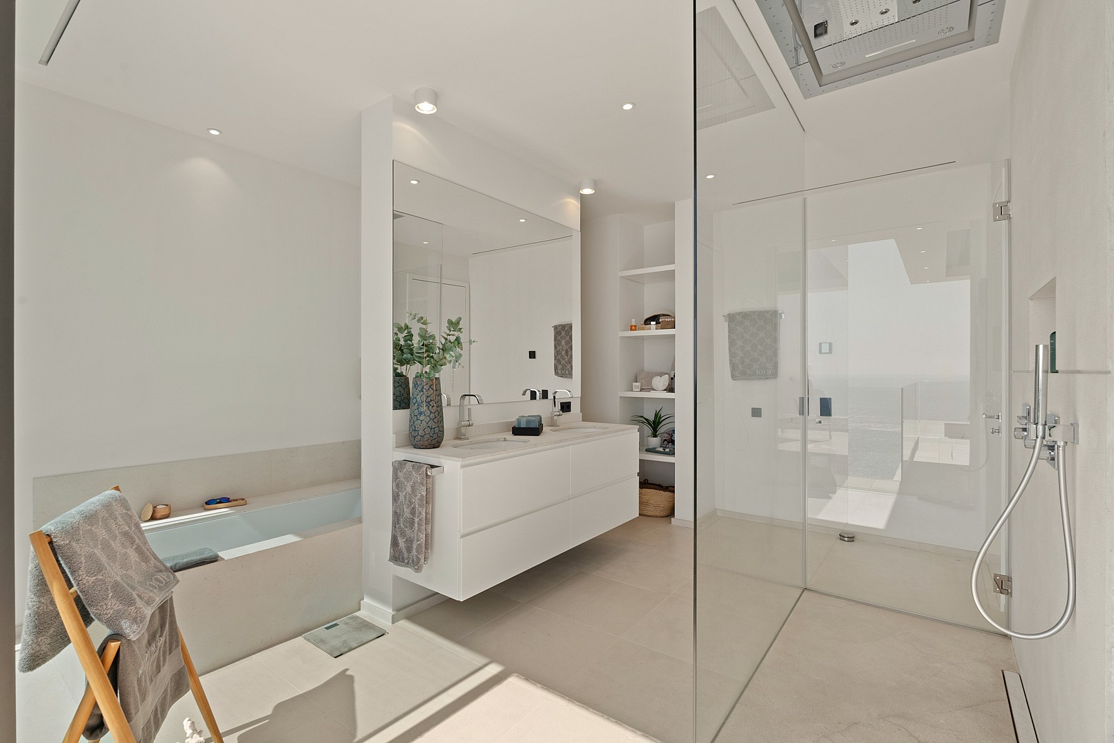 Minimalist bathroom featuring a floating white vanity, a walk-in glass shower, and a built-in bathtub on the left.