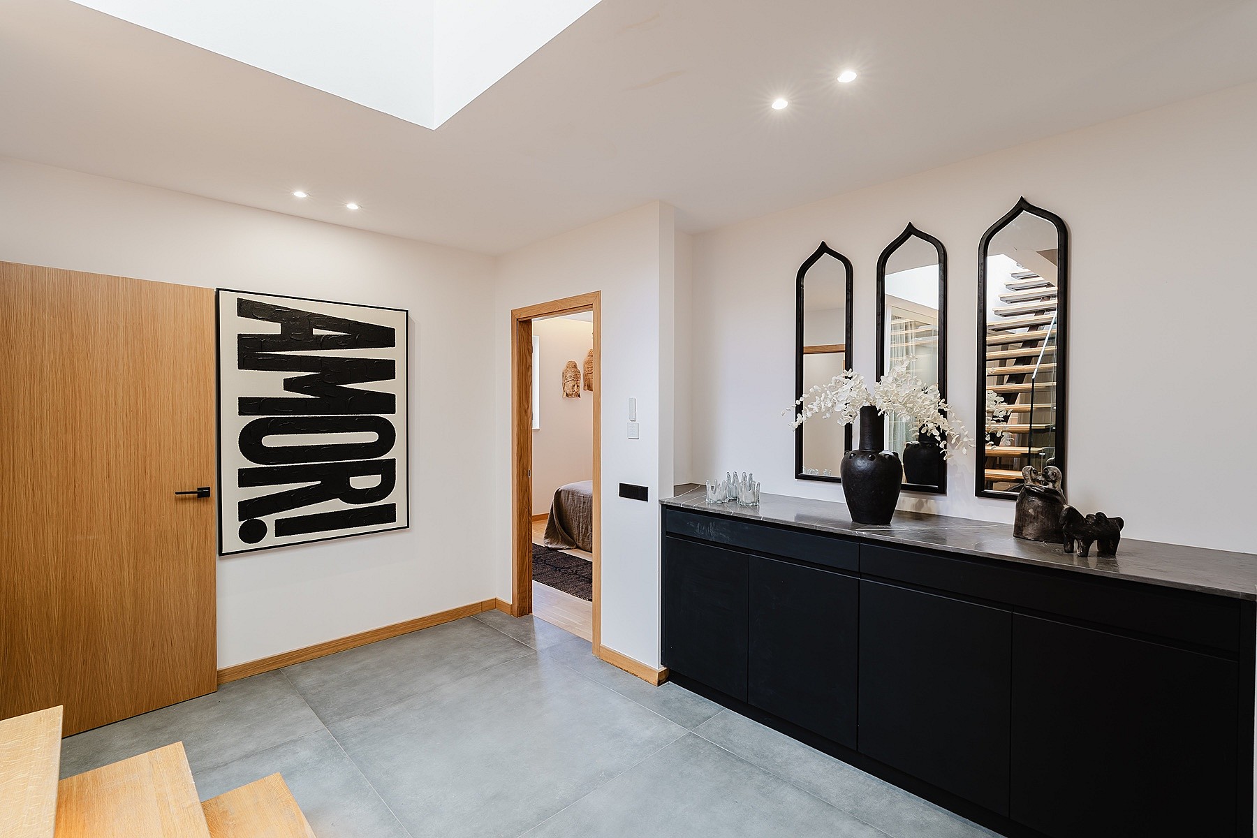 Interior hallway of an apartment in Santa Catalina with concrete floors, a black sideboard, and a skylight.