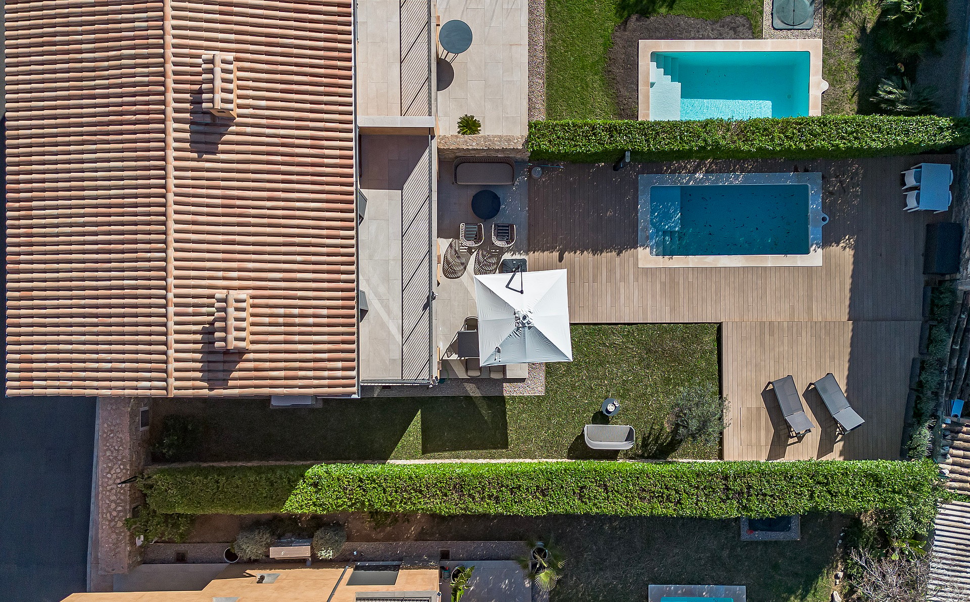 Top-down aerial view of a townhouse terrace, a rectangular swimming pool, and a manicured lawn enclosed by hedges.