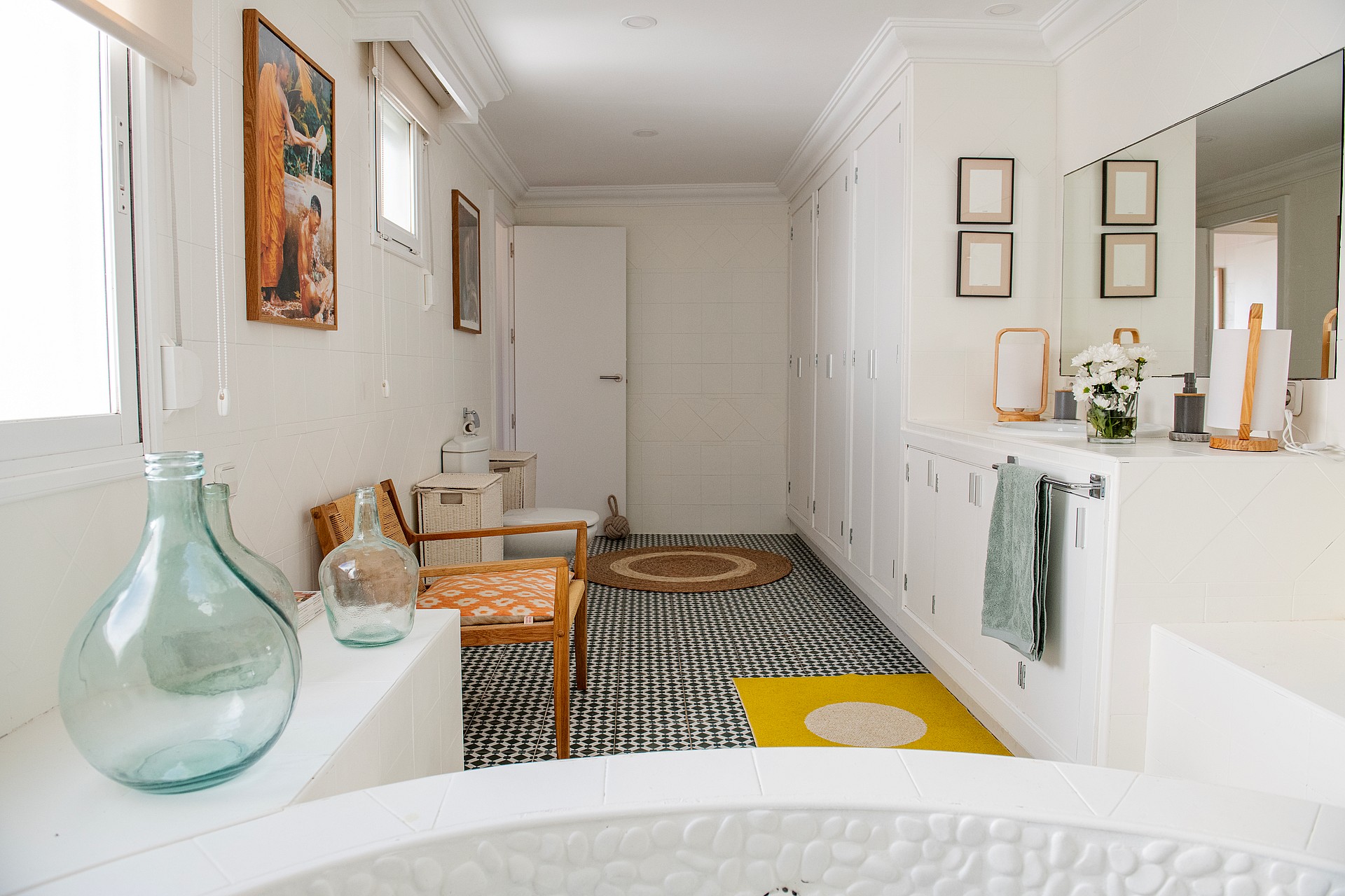 A bright bathroom with white walls, a patterned monochrome floor, and a large round basin in the foreground.
