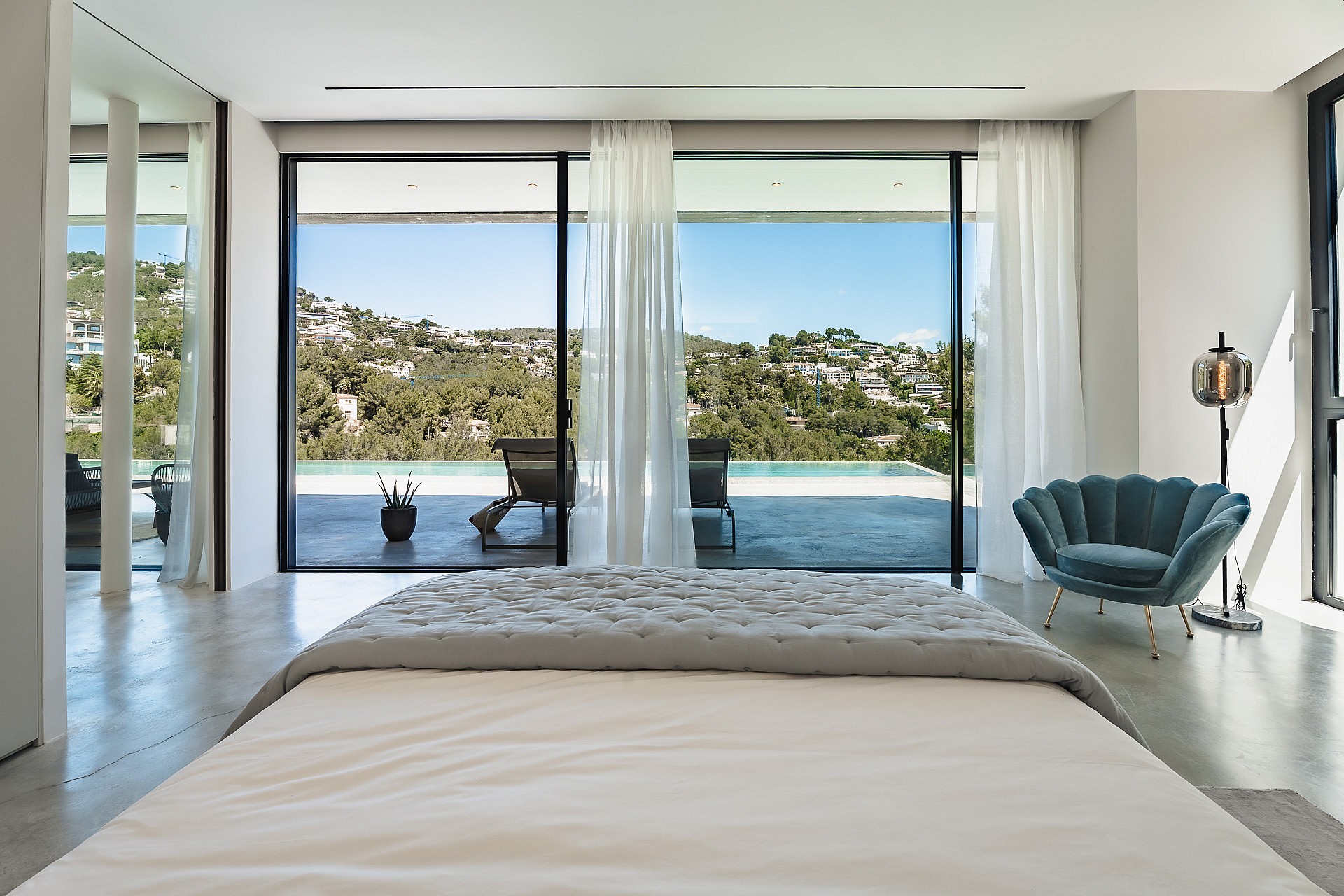 Contemporary master bedroom with large sliding glass doors facing a swimming pool and the Son Vida hills.