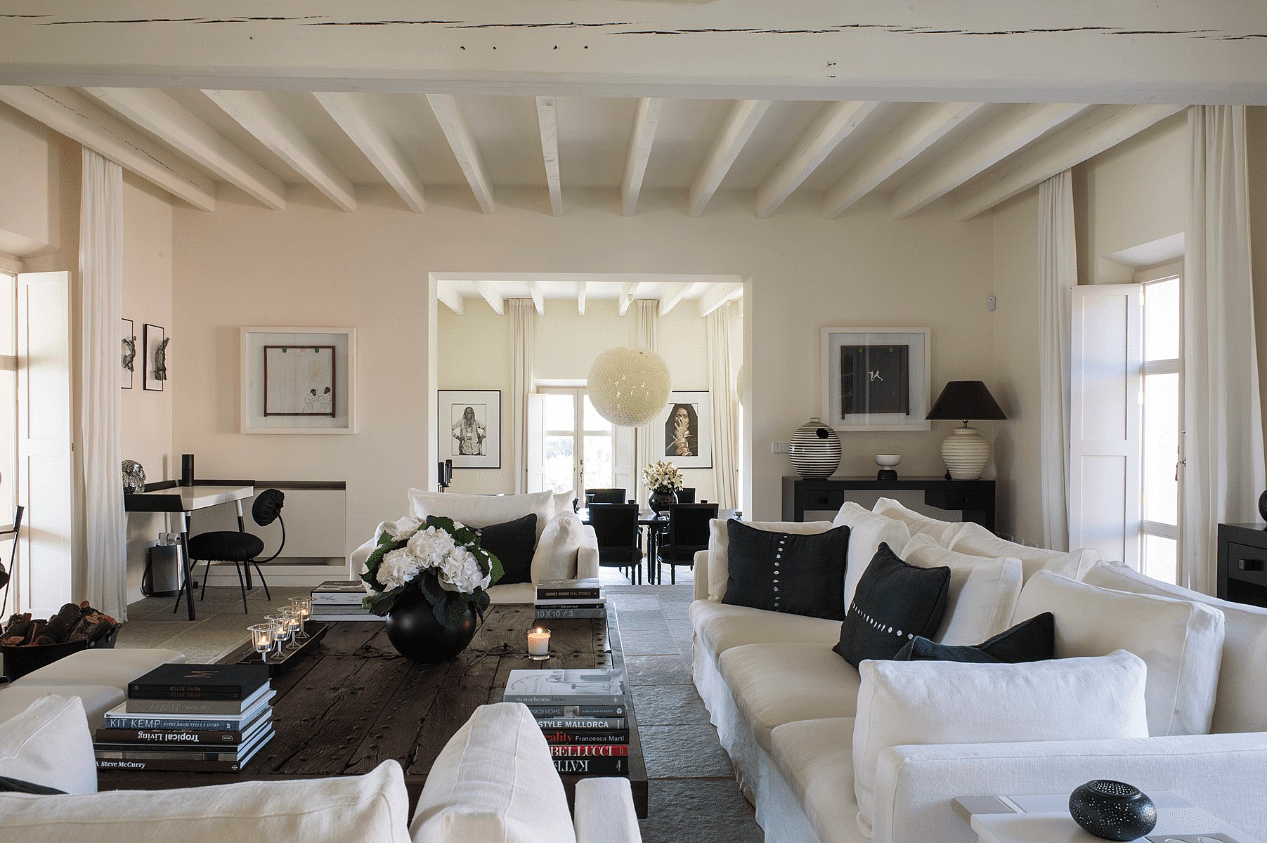 Spacious living room with white sofas, dark wooden coffee table, and beamed ceilings in a finca setting.