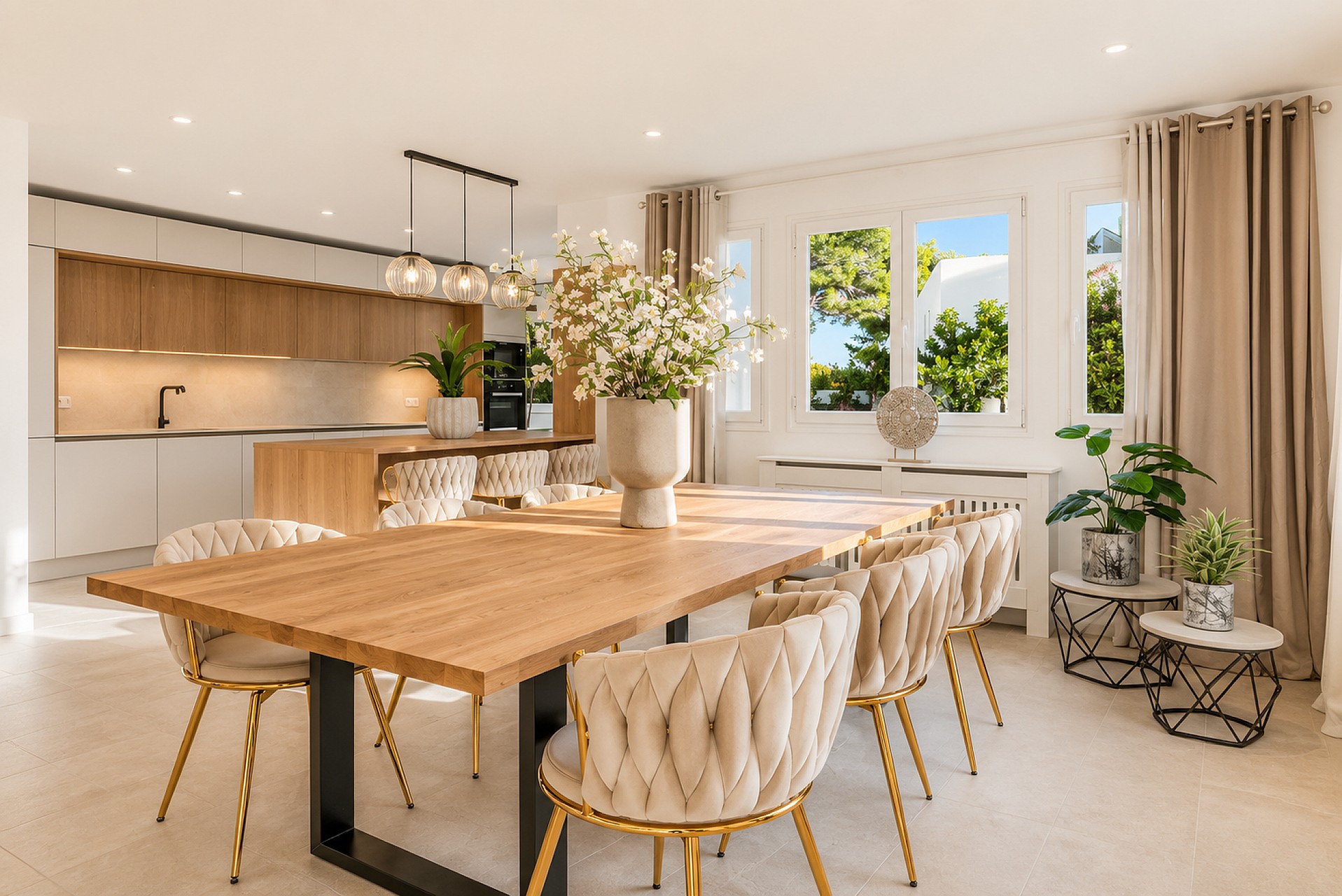 Renovated open-plan kitchen with oak cabinetry, dining table with cream tufted chairs and pendant lights