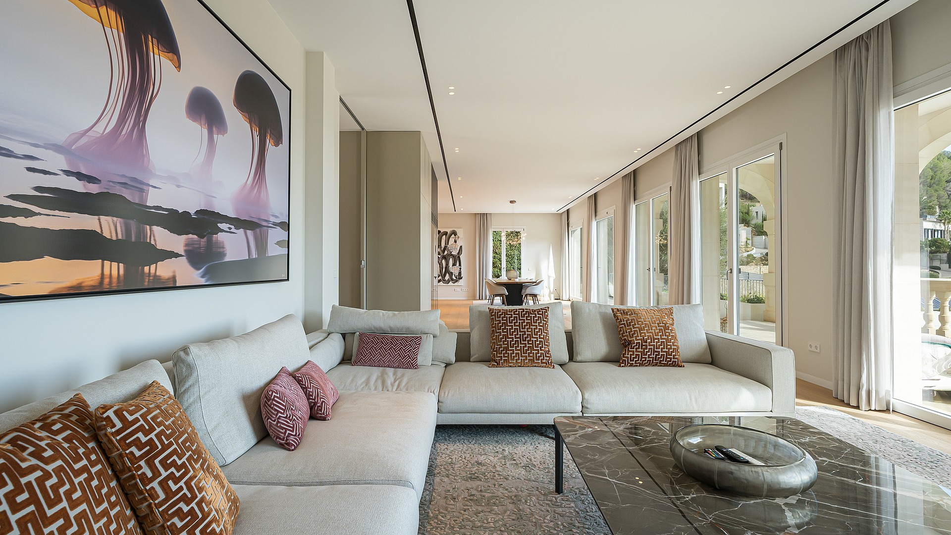 Spacious living room featuring a large sectional sofa, glass coffee table, and large abstract wall art in a modern villa.